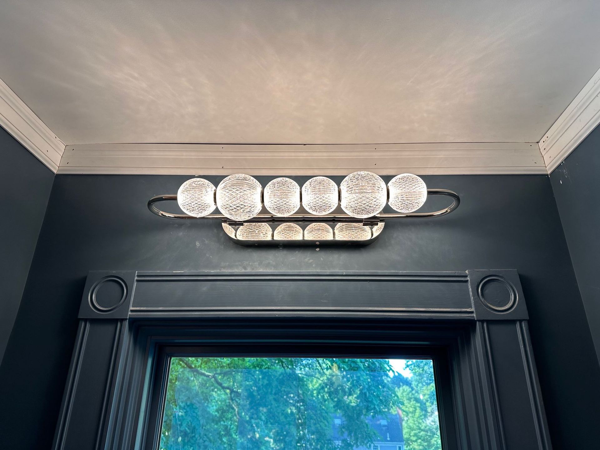 A bathroom vanity light is hanging from the ceiling above a window.