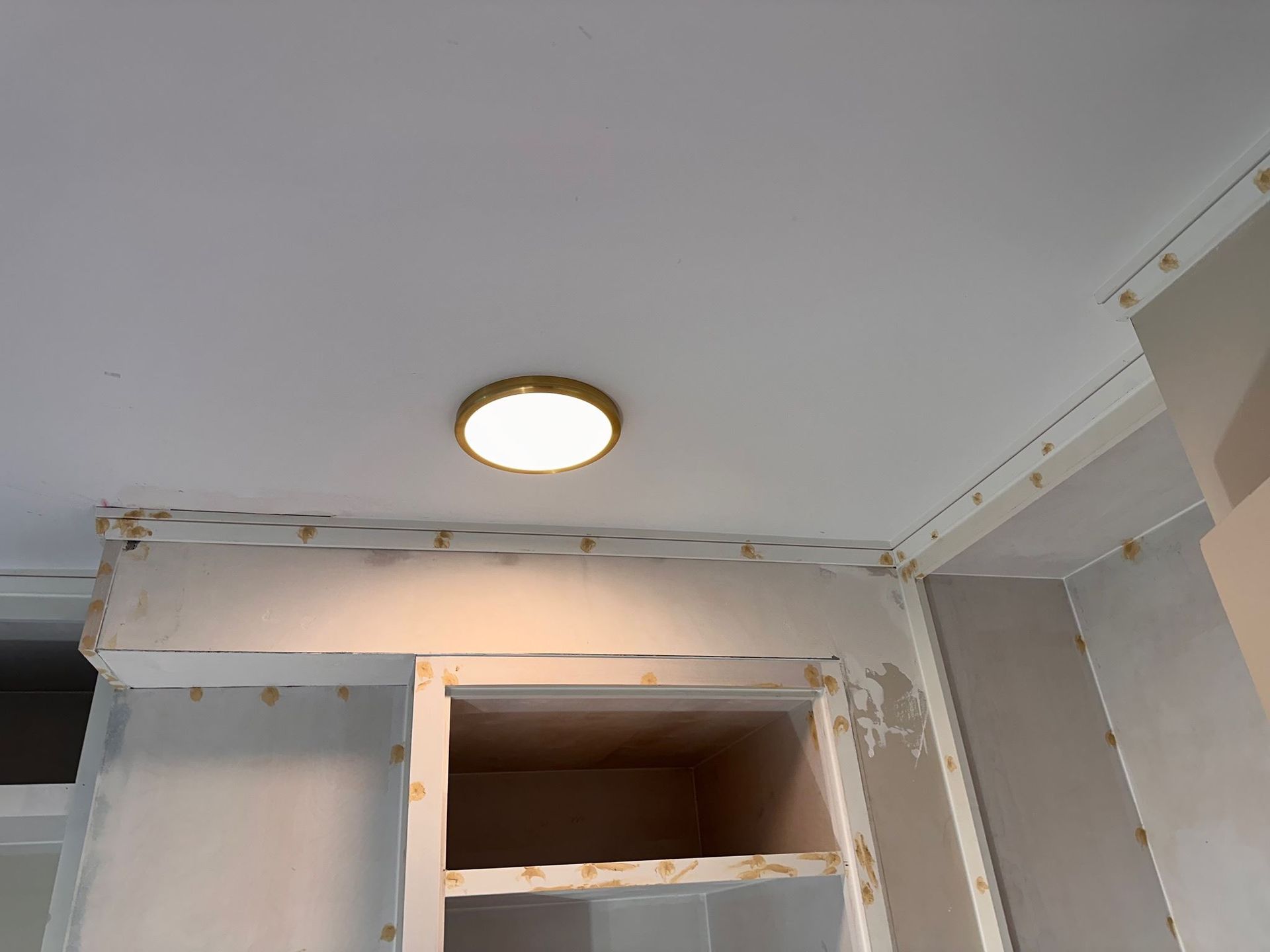 A ceiling light is above a shelf in a room