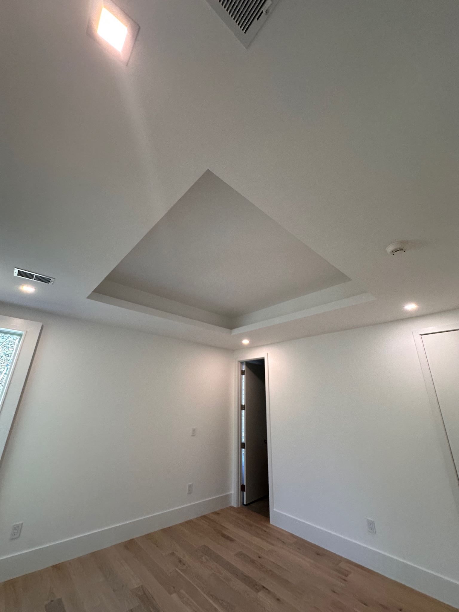 An empty room with hardwood floors and white walls.