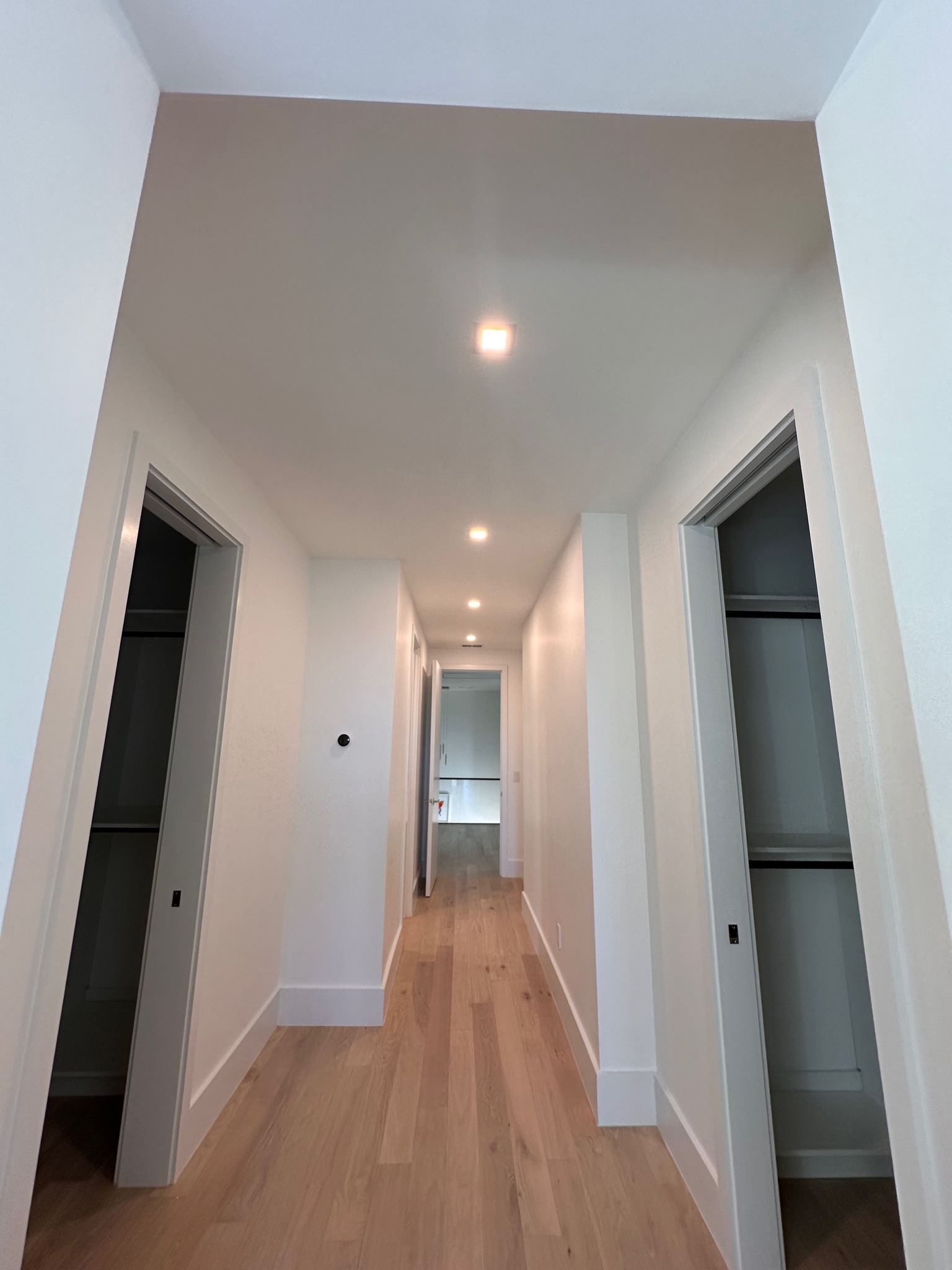 A long hallway with hardwood floors and white walls