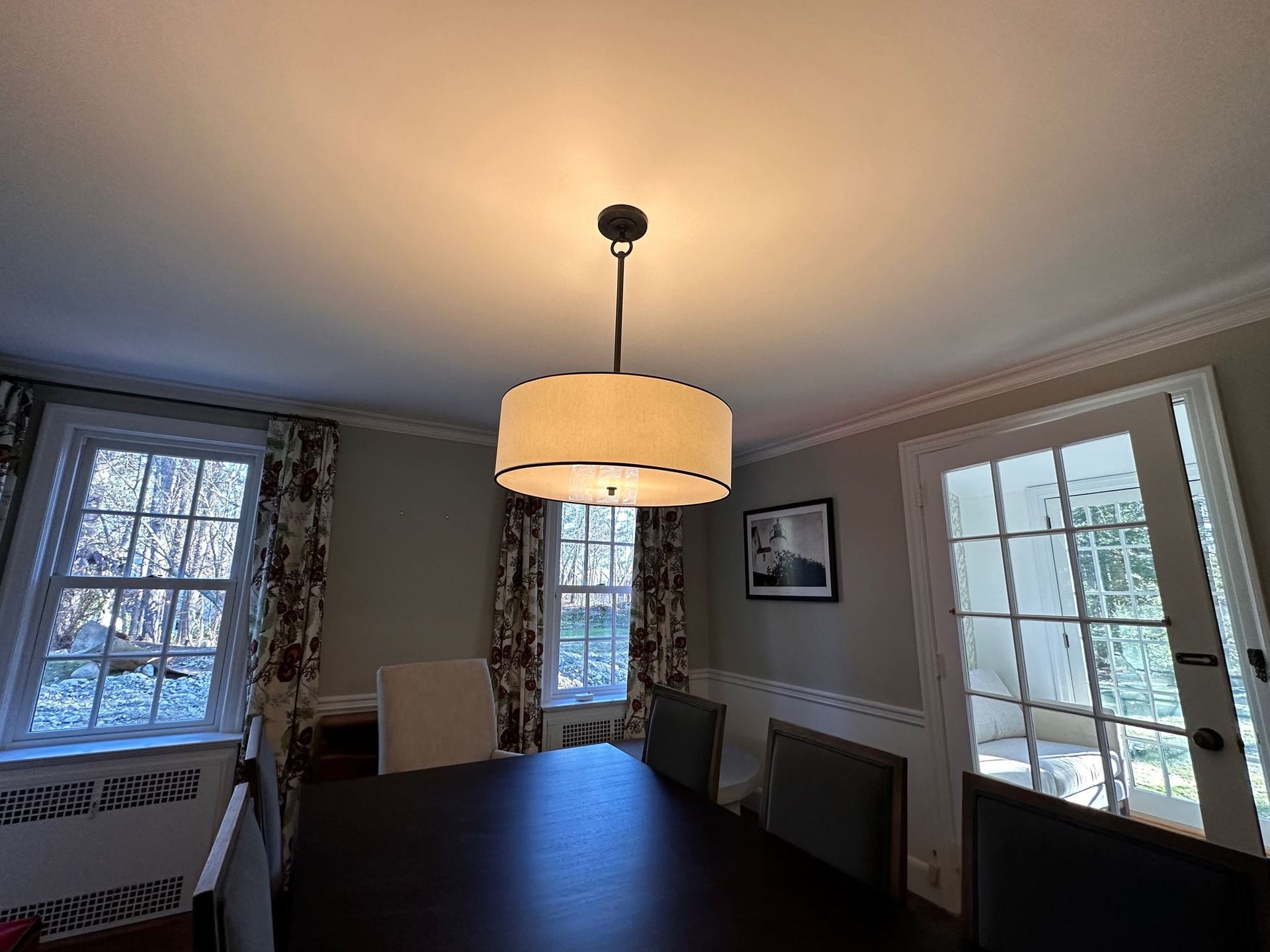 A dining room with a table and chairs and a chandelier hanging from the ceiling.