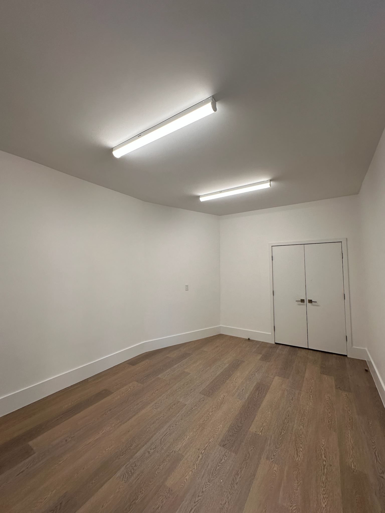 An empty room with hardwood floors and white walls.