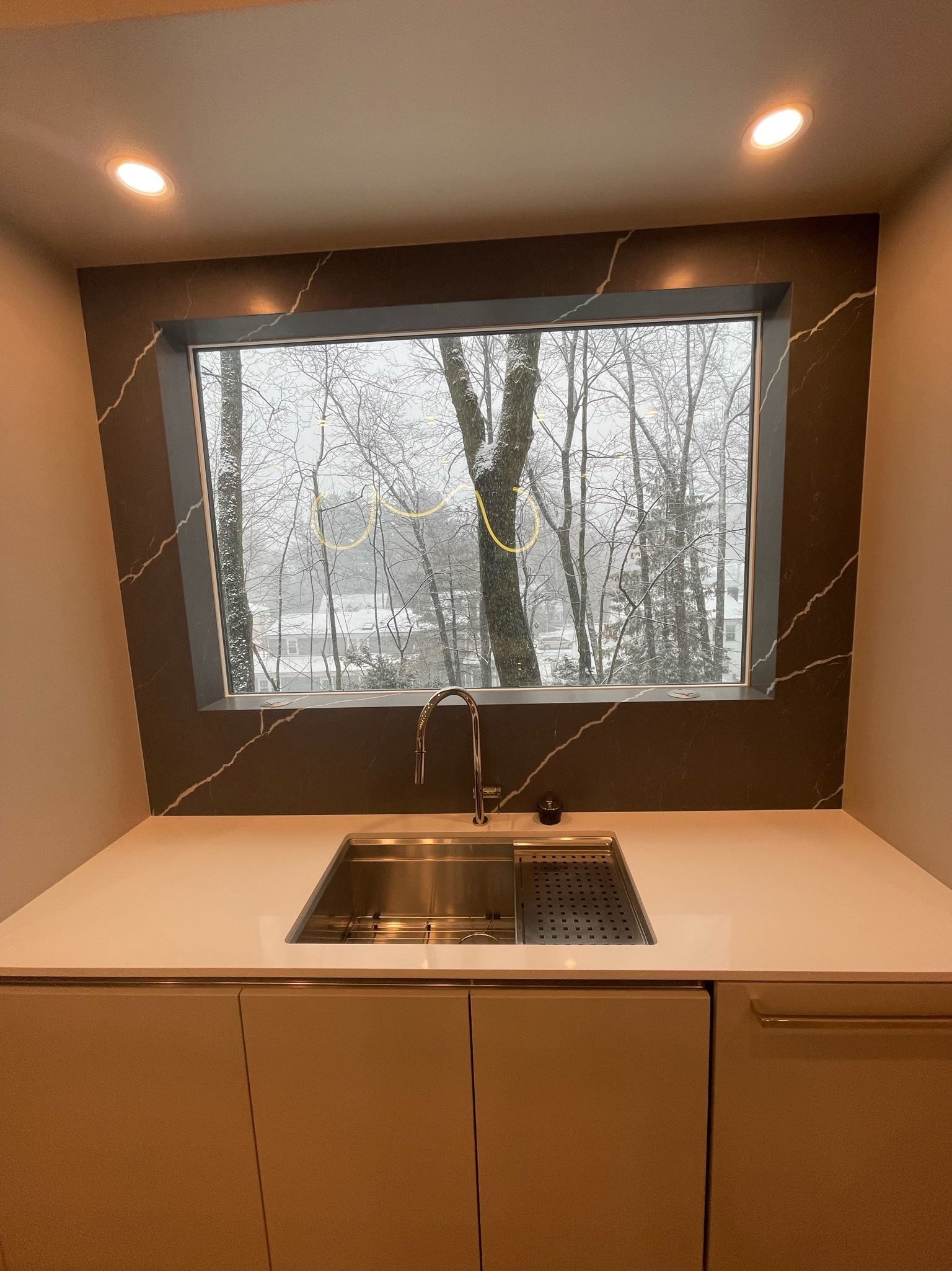 A kitchen with a sink and a window with trees in the background