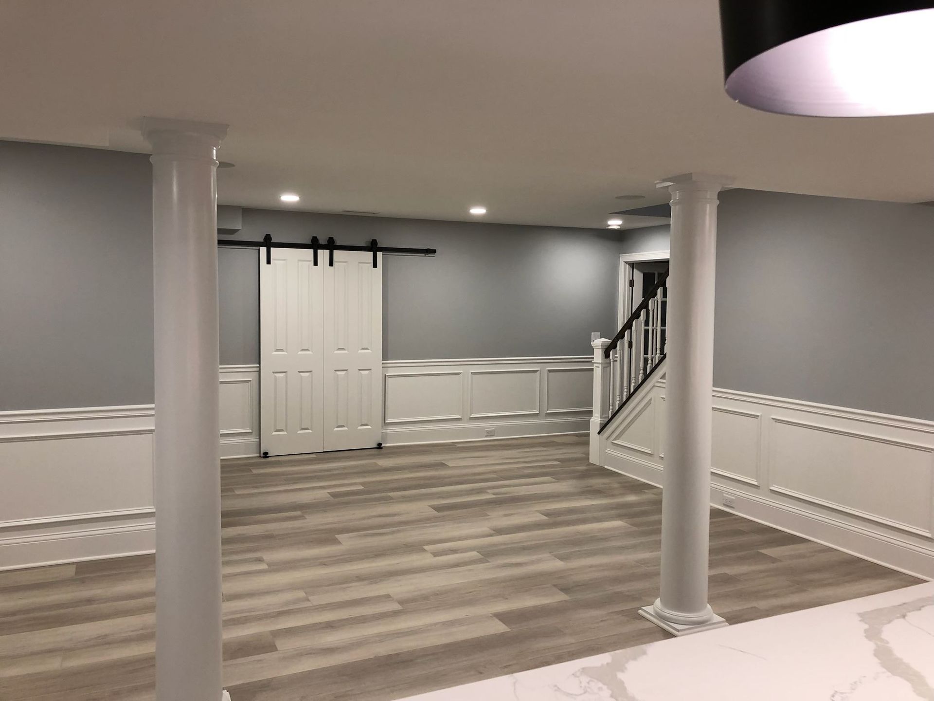 An empty basement with a sliding barn door and stairs