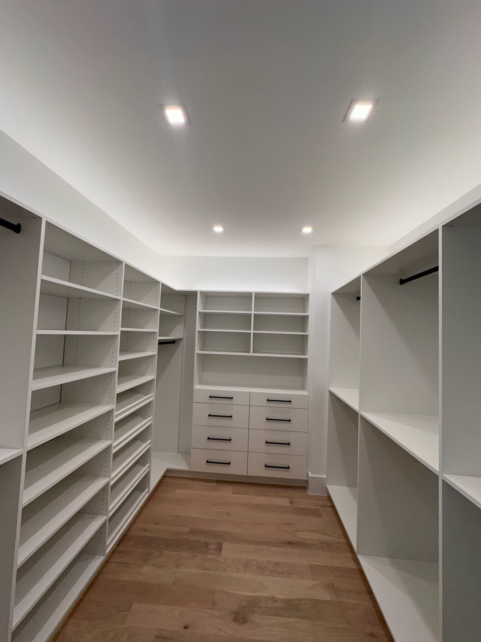 A walk in closet with lots of shelves and drawers.