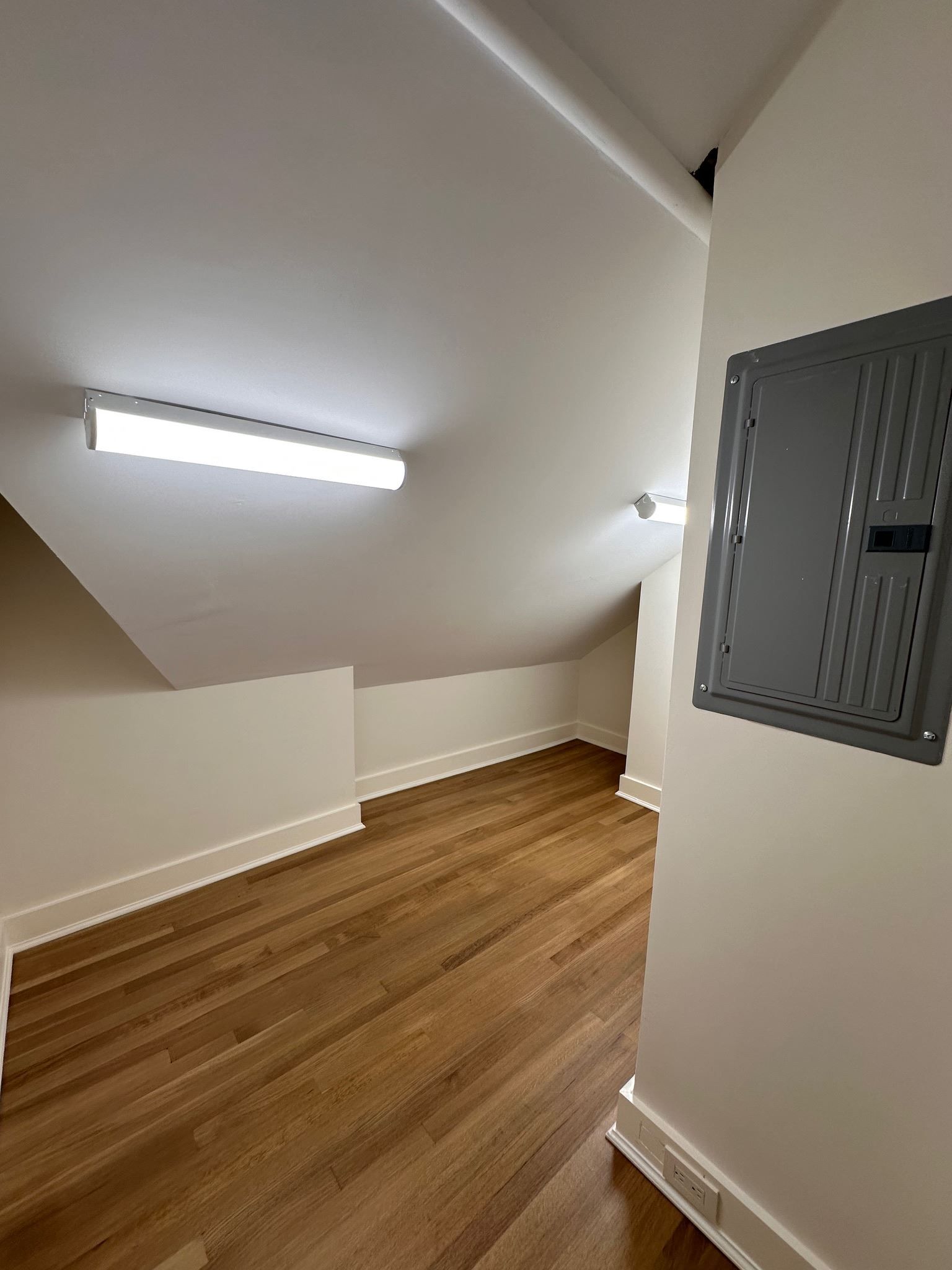 A room with hardwood floors and a gray box on the wall.
