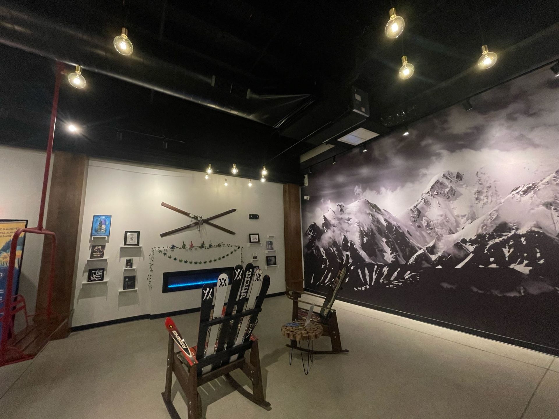 A room with a rocking chair and a picture of mountains on the wall.