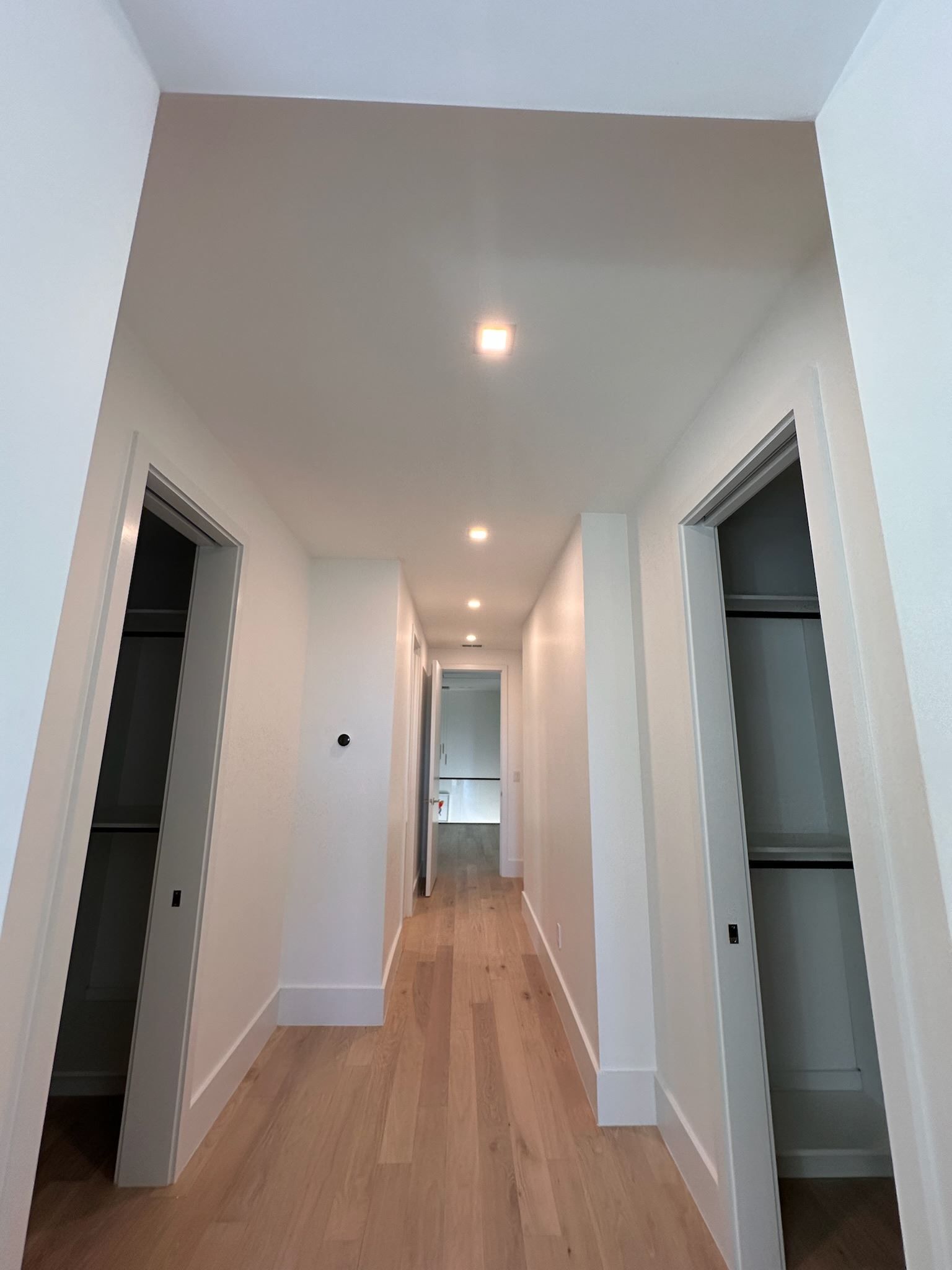 A long hallway with hardwood floors and white walls
