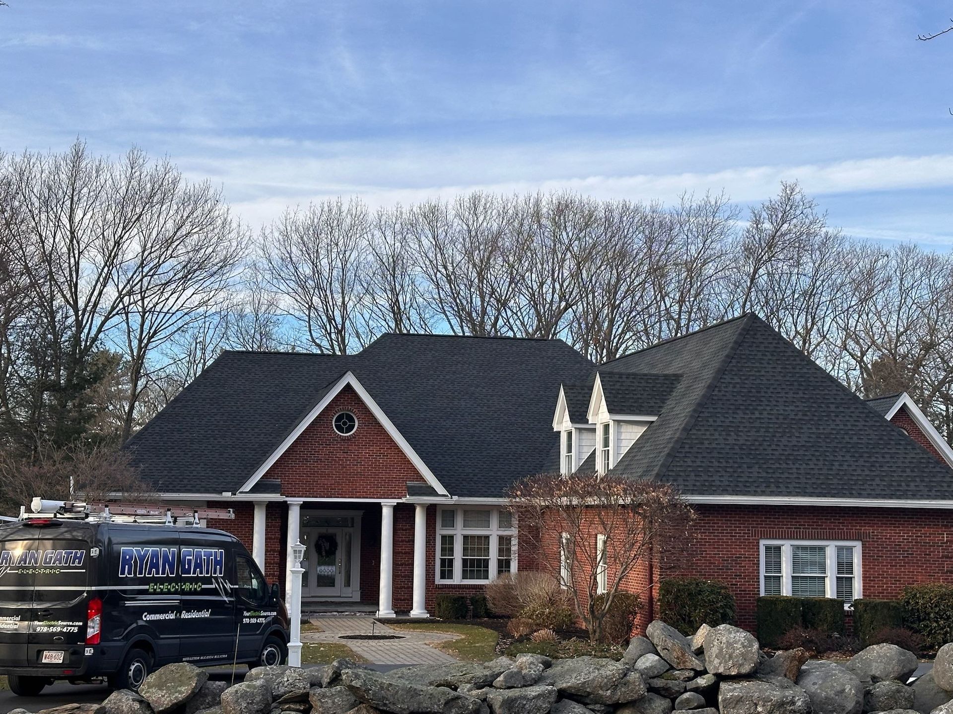 A large brick house with a black roof and a truck parked in front of it.