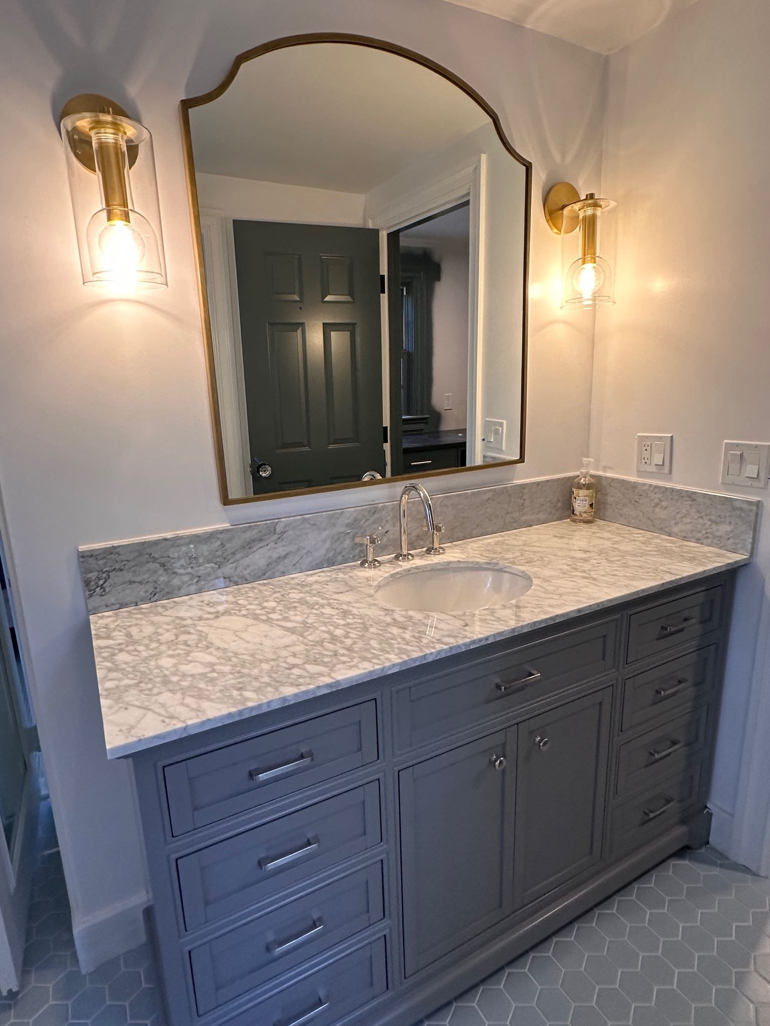 A bathroom with a sink , mirror and cabinets.