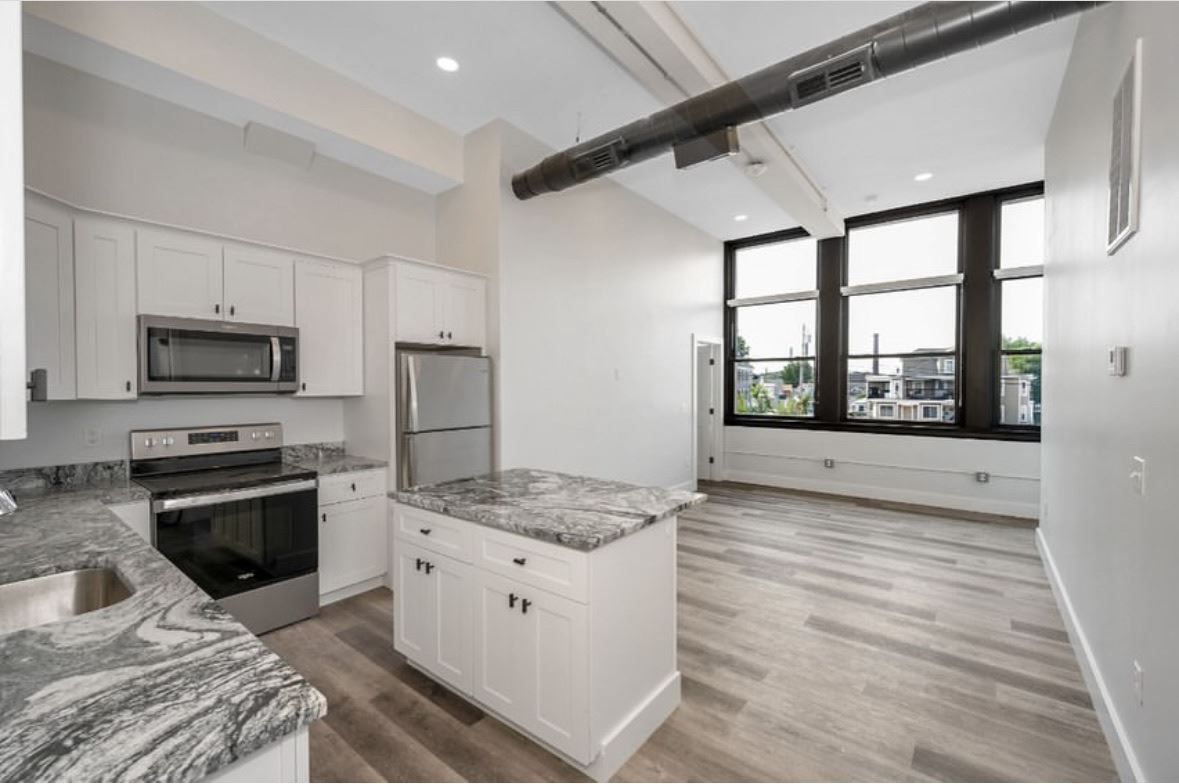 A kitchen with white cabinets , granite counter tops , stainless steel appliances and a large island.