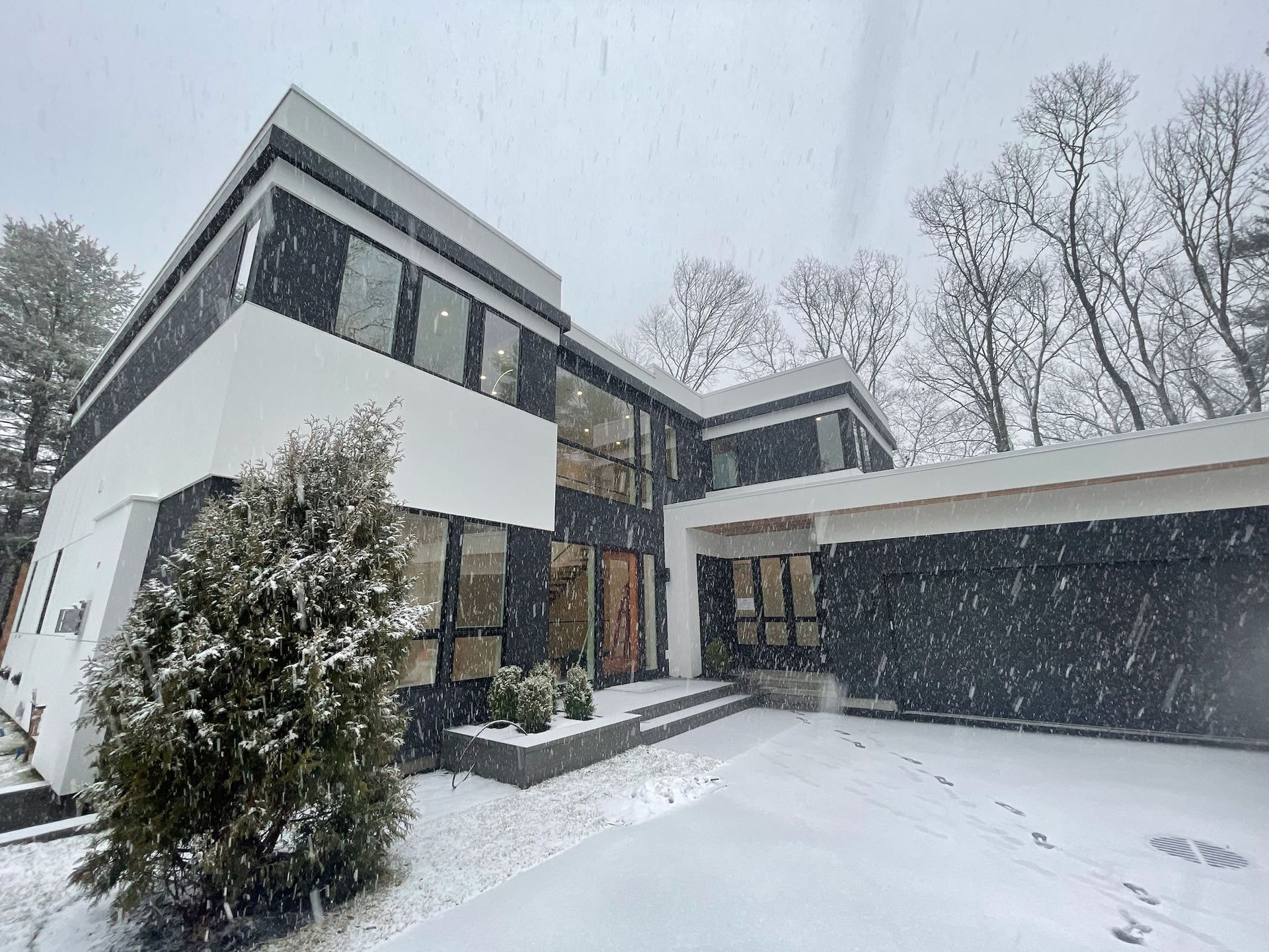 A large house with a lot of windows is covered in snow.