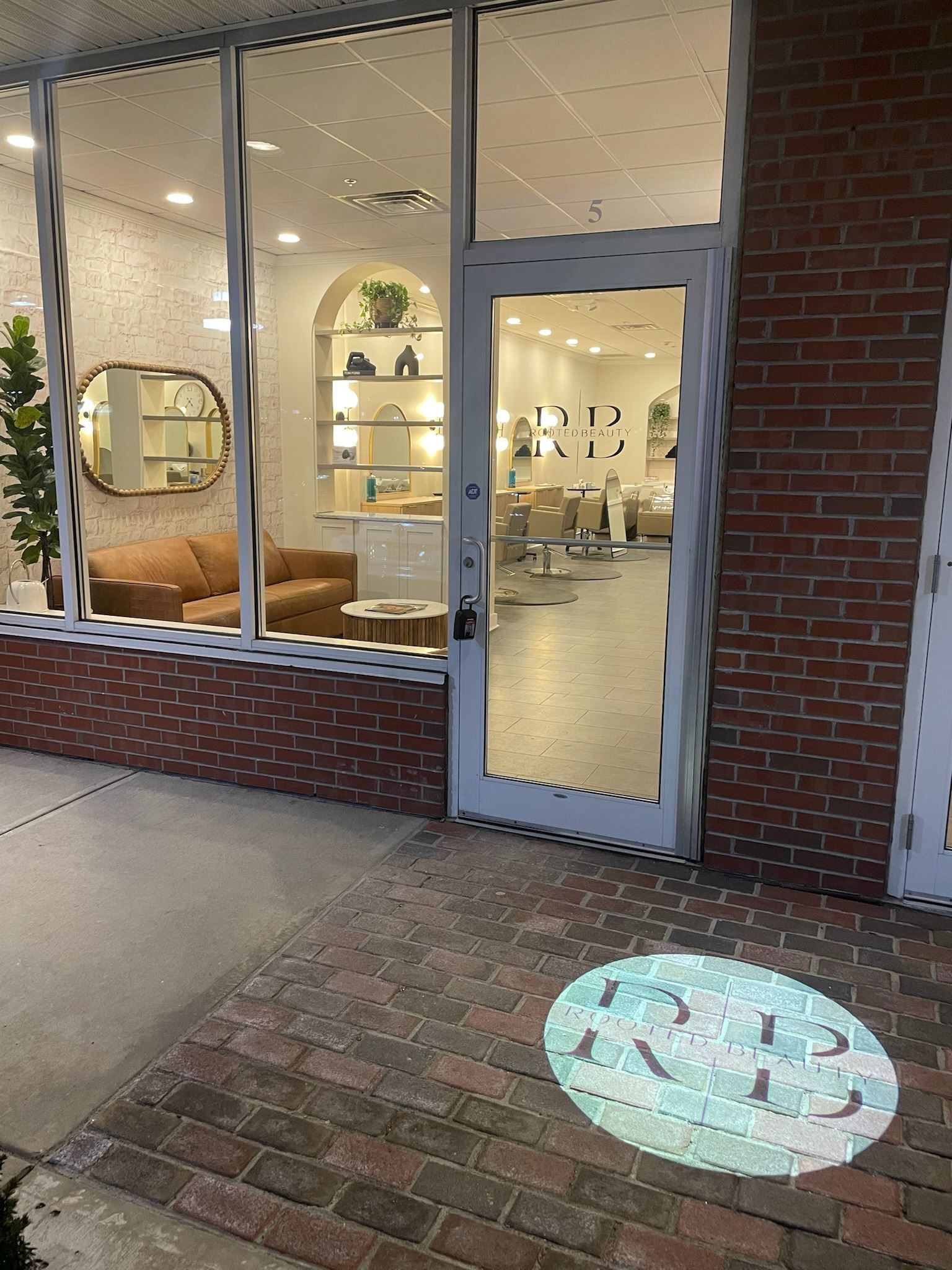 A brick building with a glass door and a logo on the sidewalk.