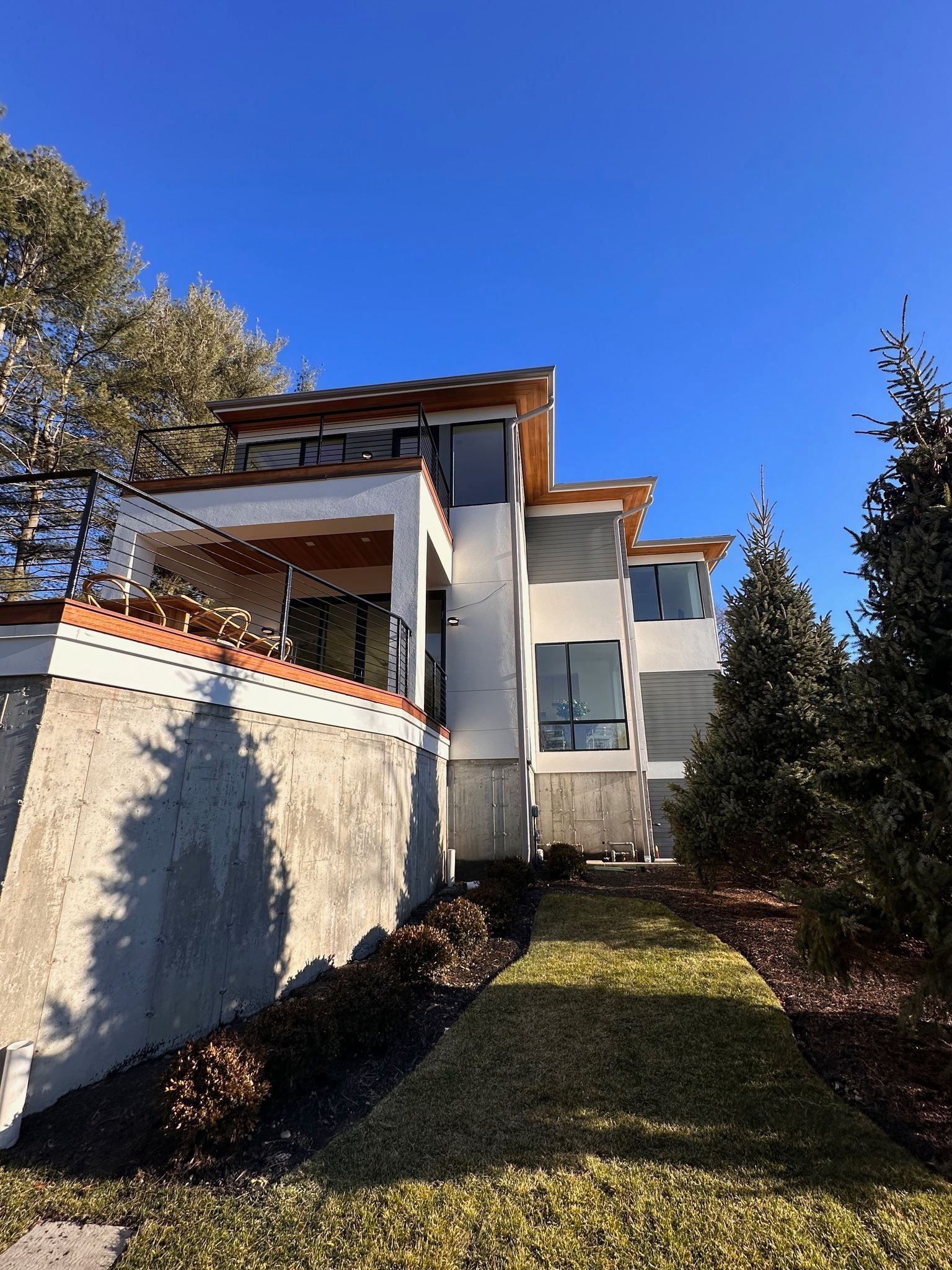 A large white house is sitting on top of a hill surrounded by trees.