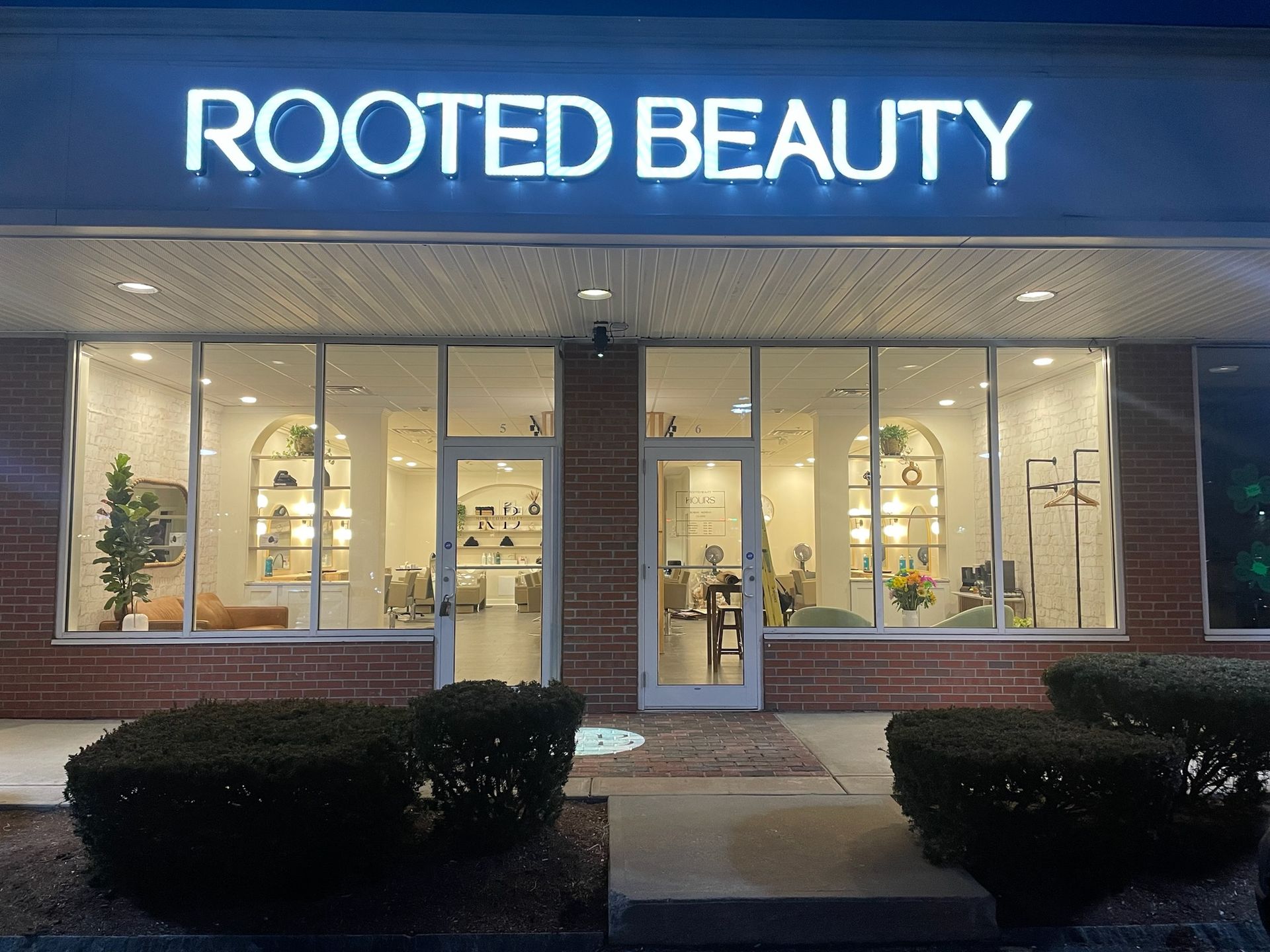 The front of a rooted beauty salon is lit up at night.