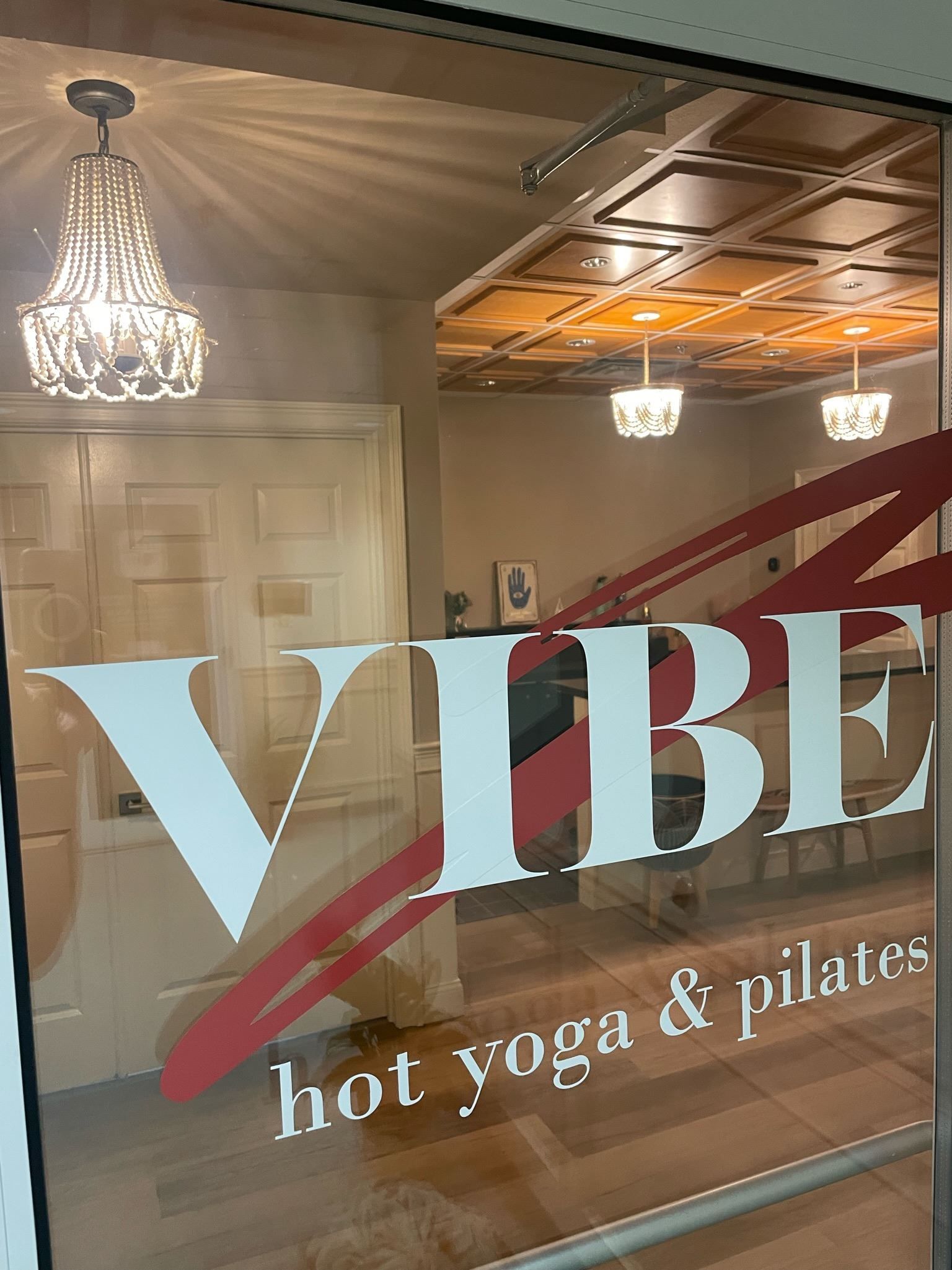 A sign for vibe hot yoga and pilates is on a window.