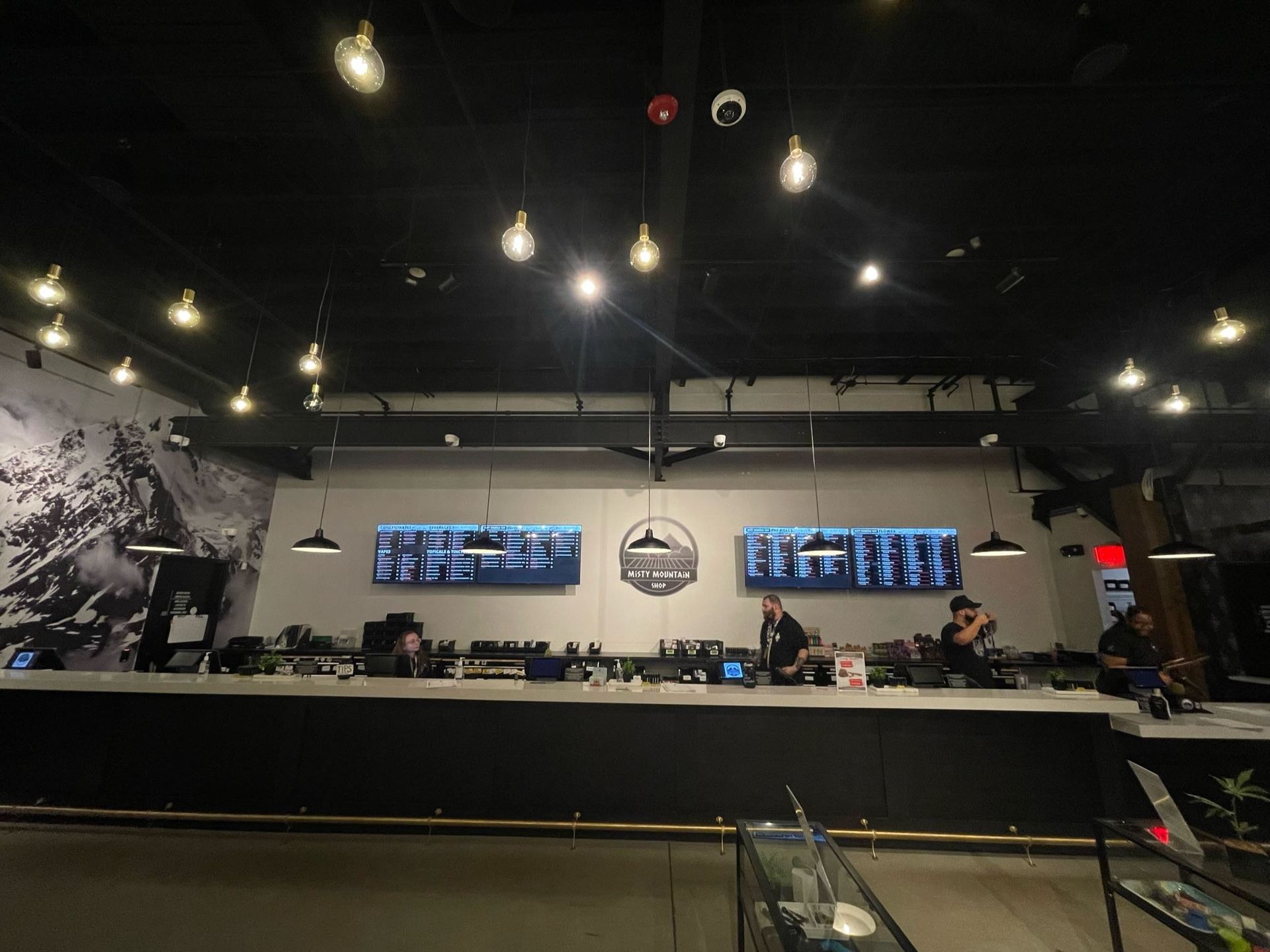 A restaurant with a long counter and a large picture on the wall.