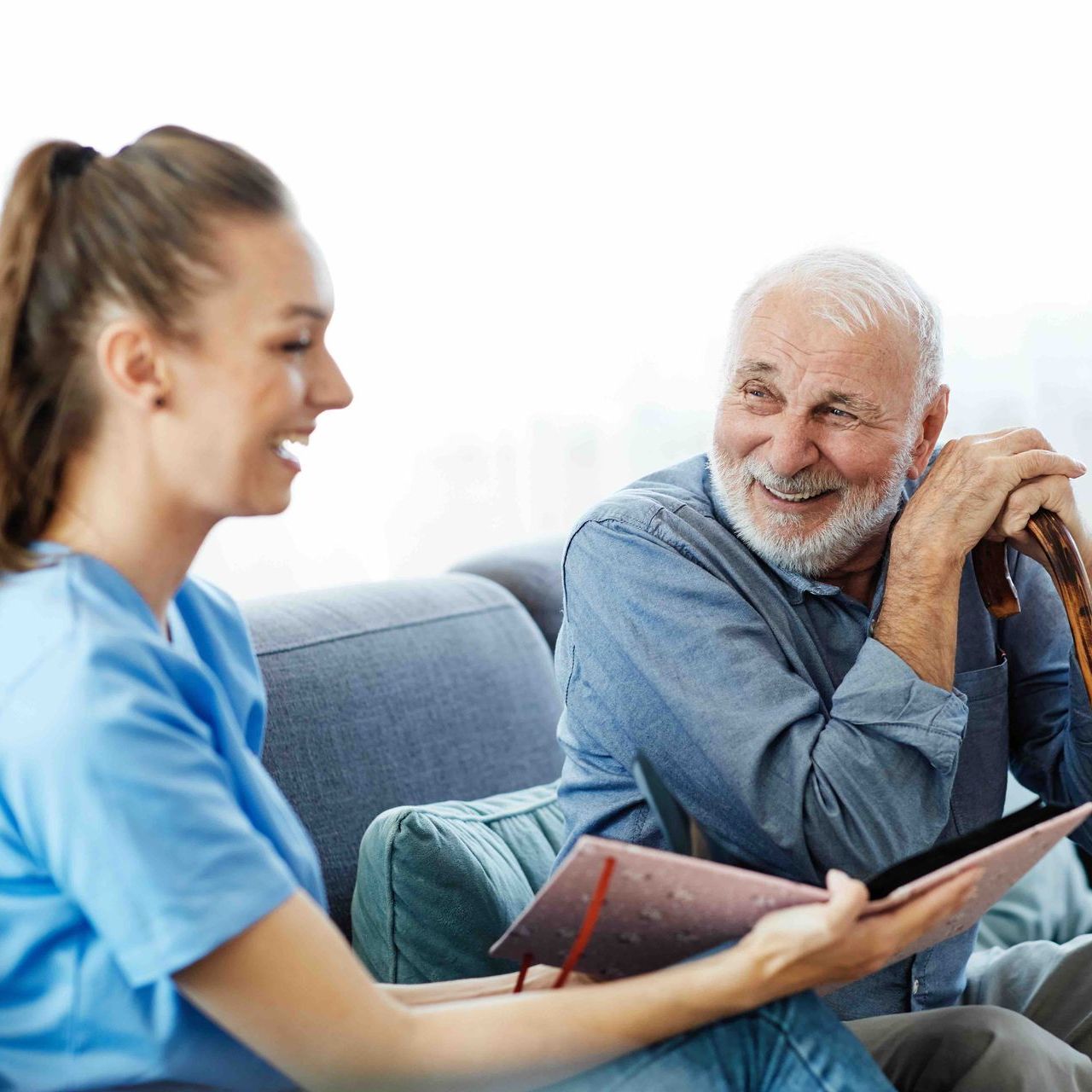 Caregiver showing an older adult a book; both are smiling.