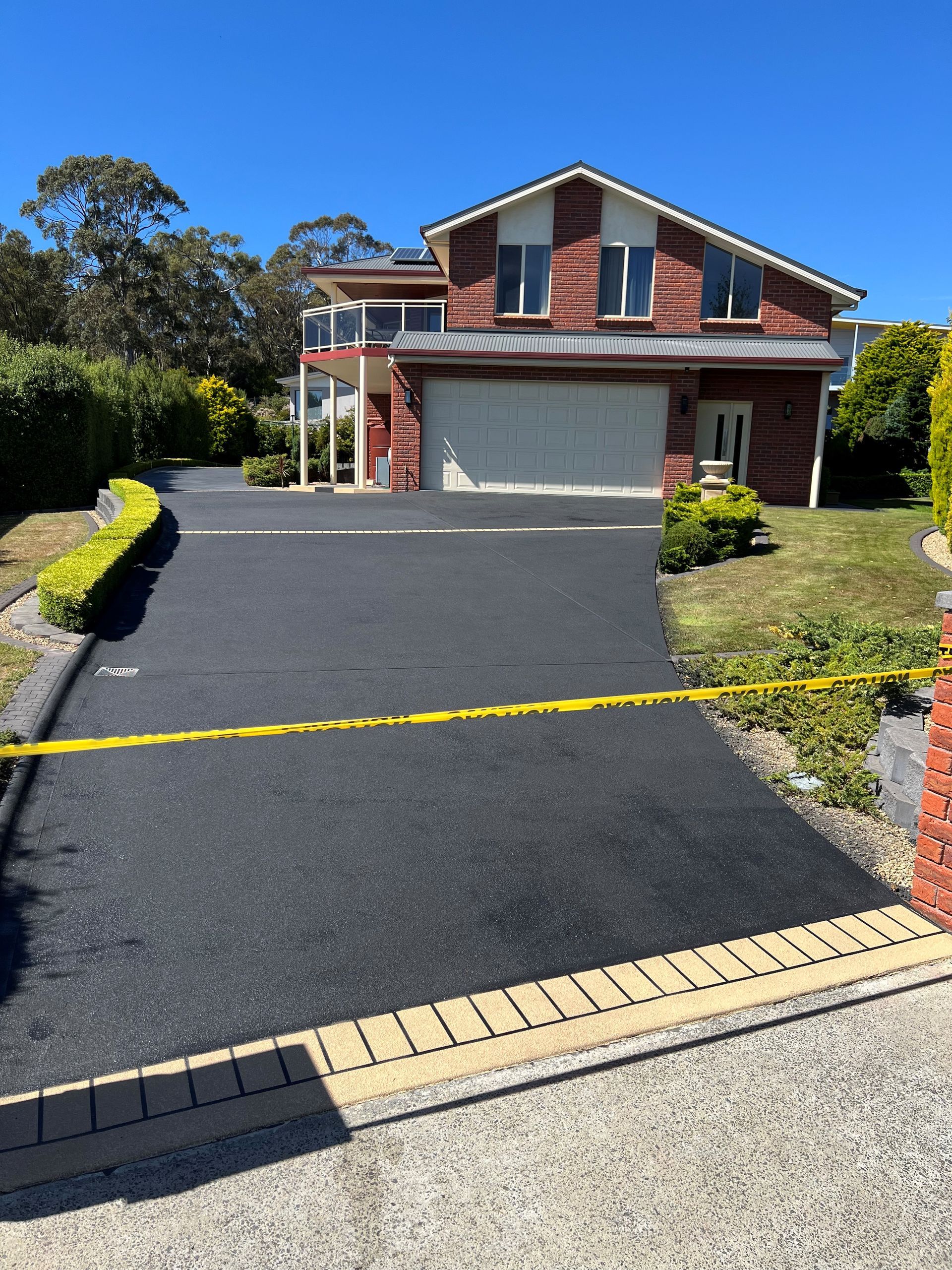 A Large Brick House with A Black Driveway — Tasmania — Concrete Concepts Tasmania Pty Ltd