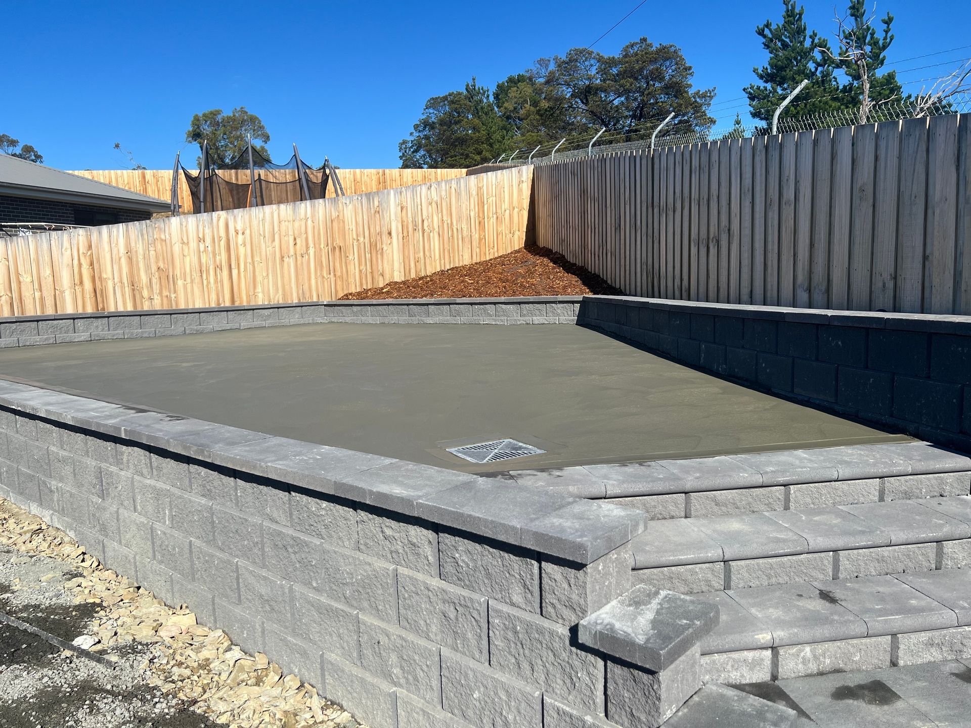 A concrete patio with a wooden fence in the background