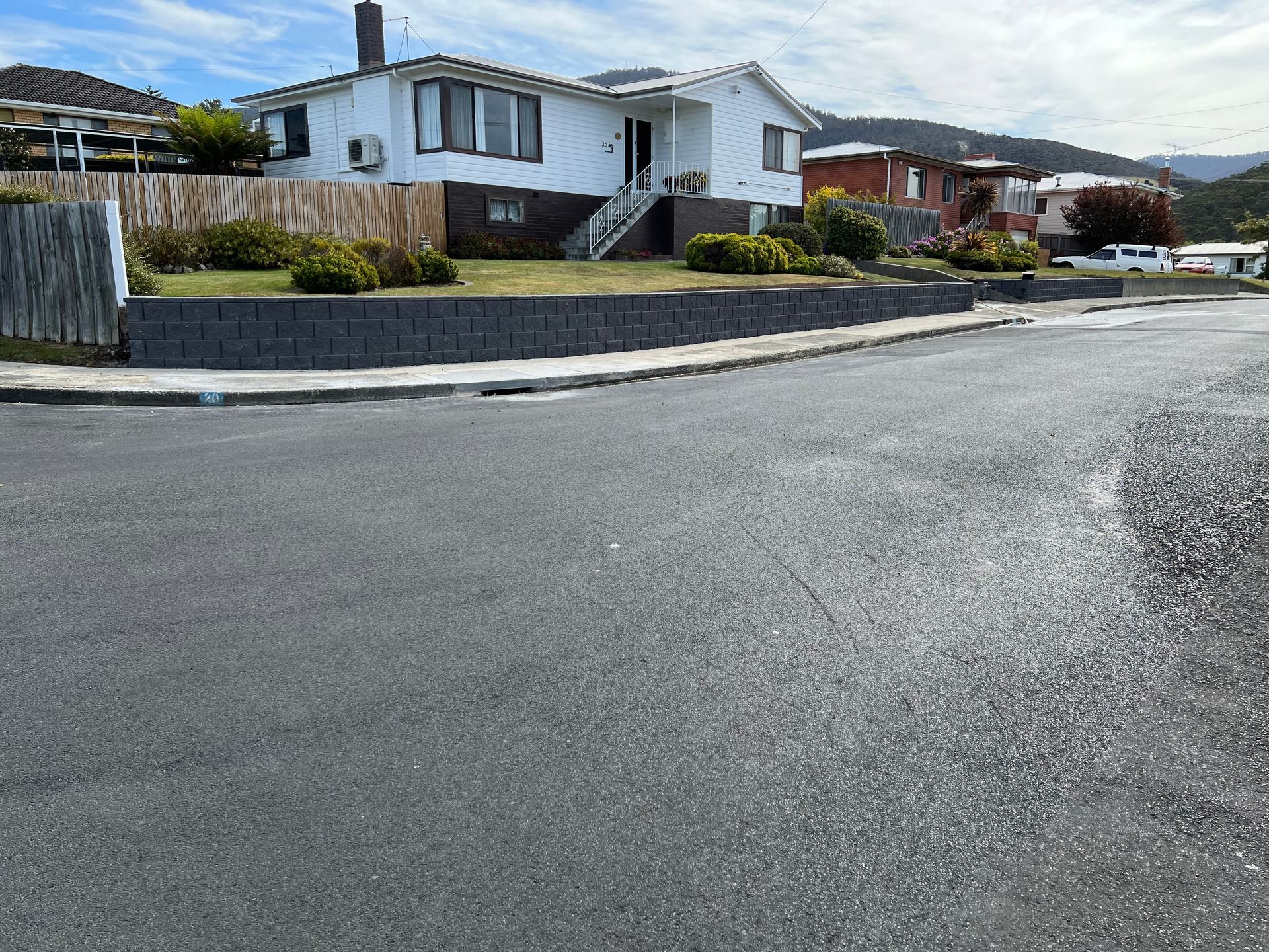 A white house is sitting on the corner of a street.
