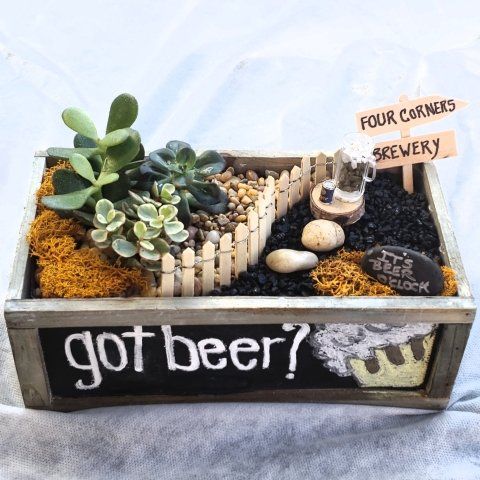 a fairy garden in a wooden box with a sign that says `` got beer ? ''