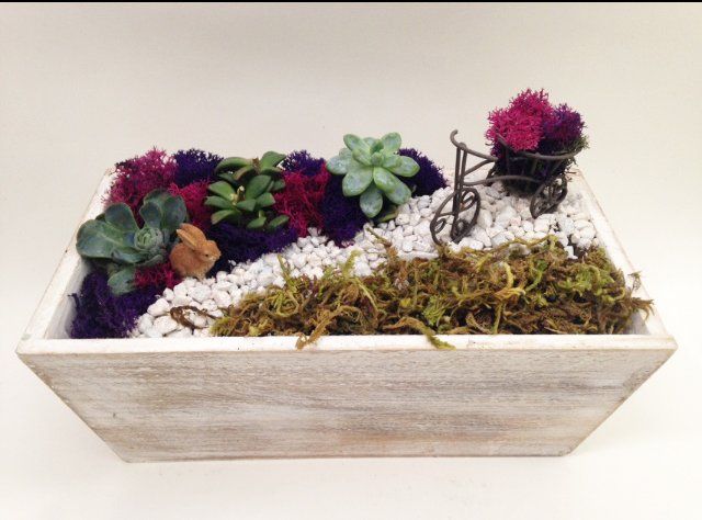 a wooden planter filled with flowers and a bicycle .