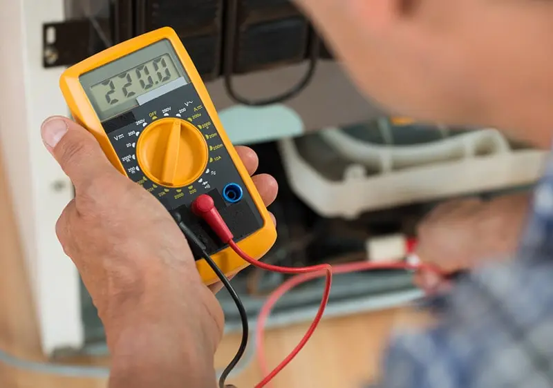 Un hombre sostiene un multímetro digital en la mano.