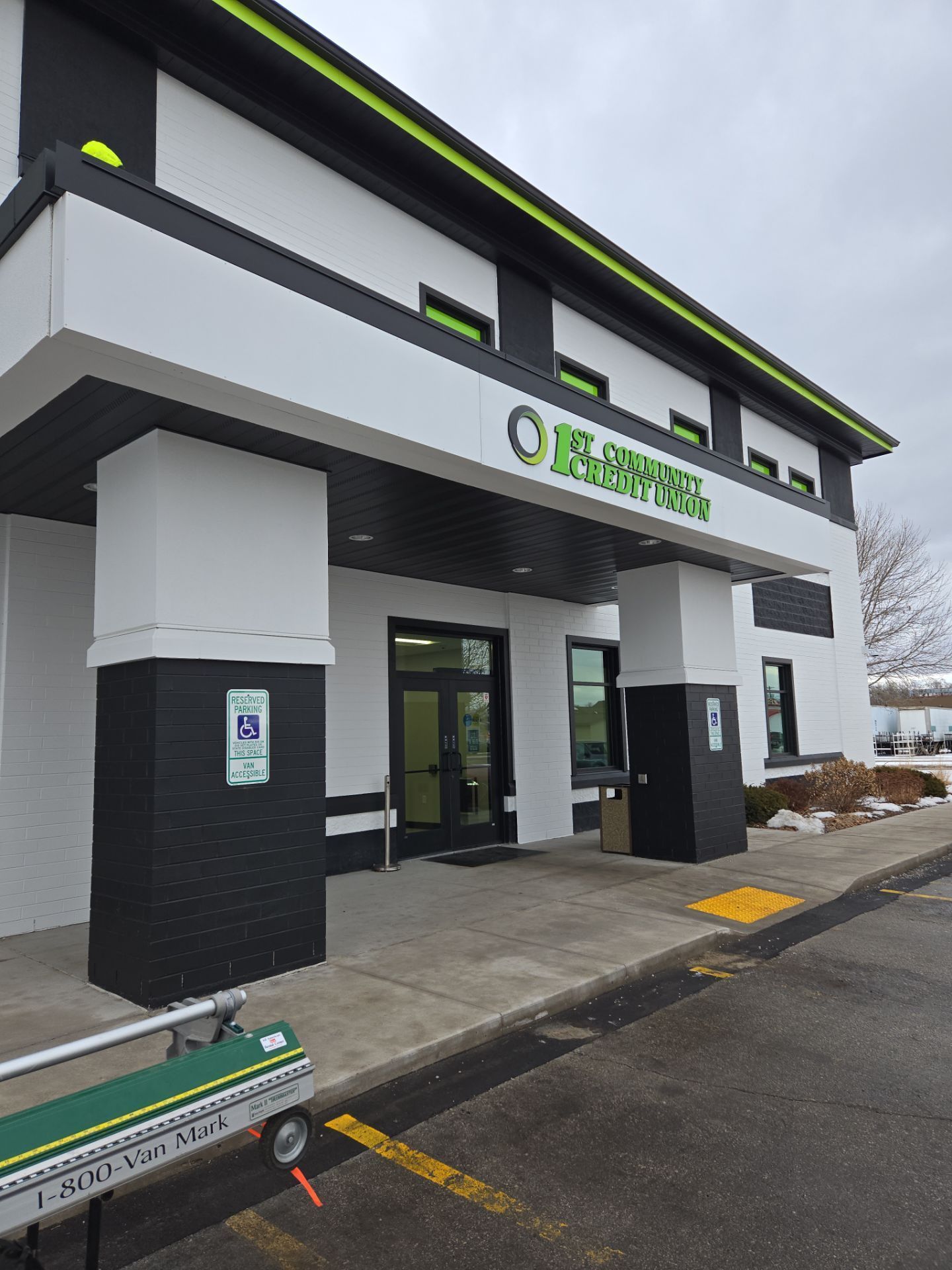 Exterior of Planet Fitness gym. Black and white building with green accents, accessible entrance.