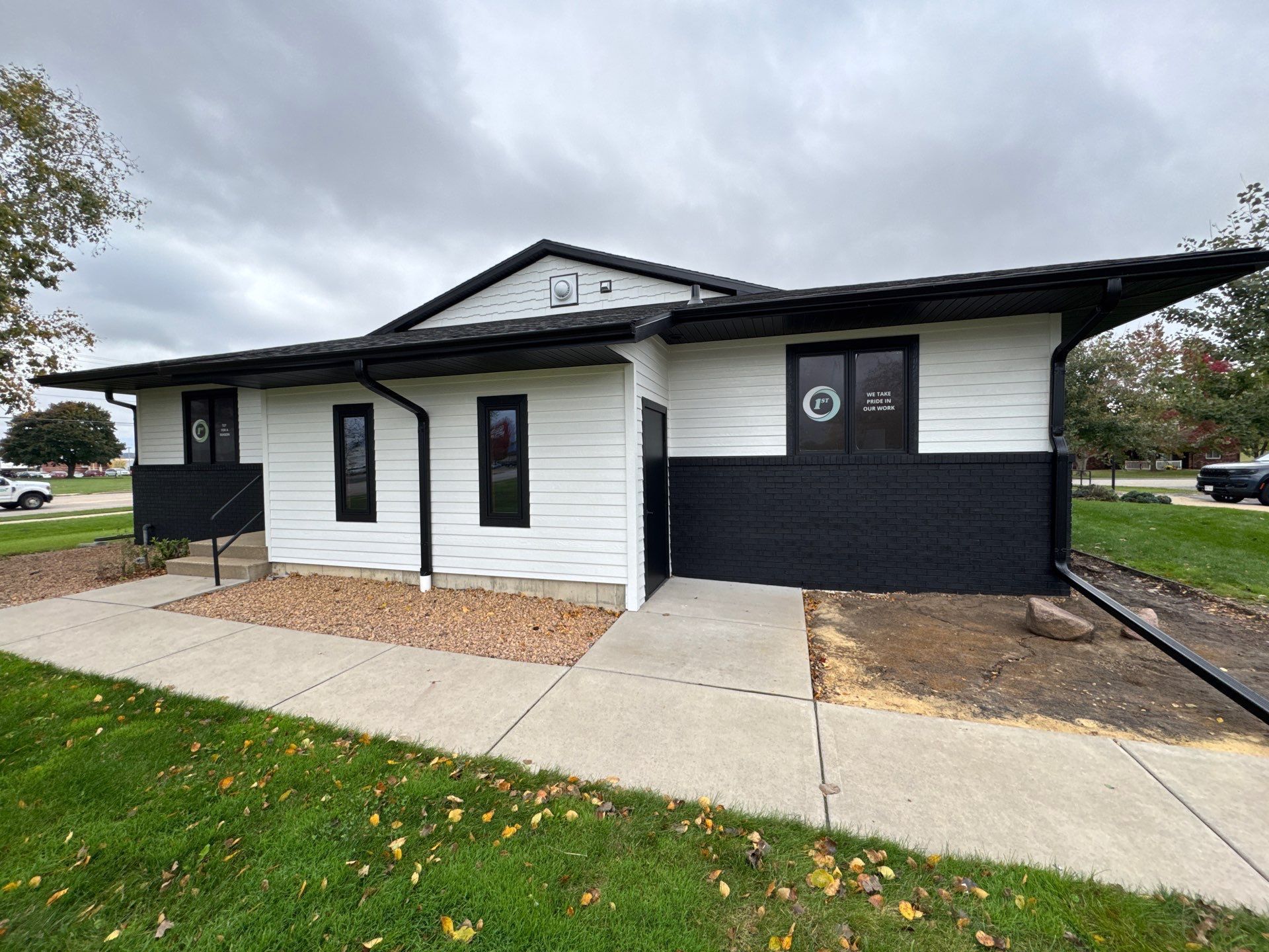 A small, modern building with white siding, black trim and a black brick facade.