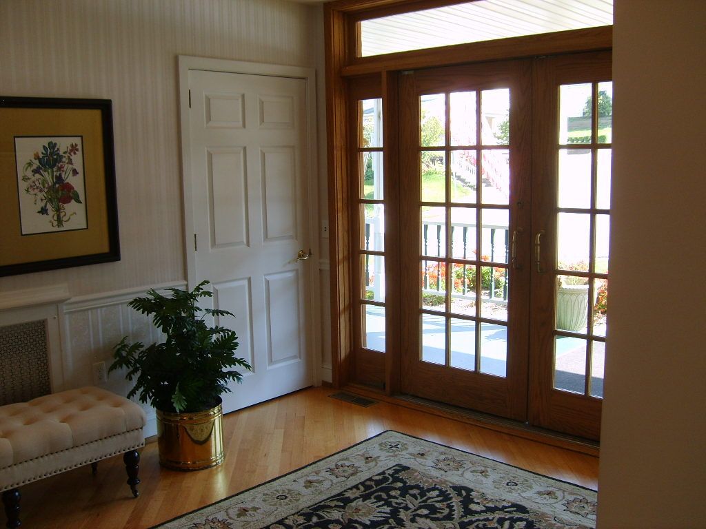 Entryway with hardwood floor, French doors, potted plant, and decorative rug.