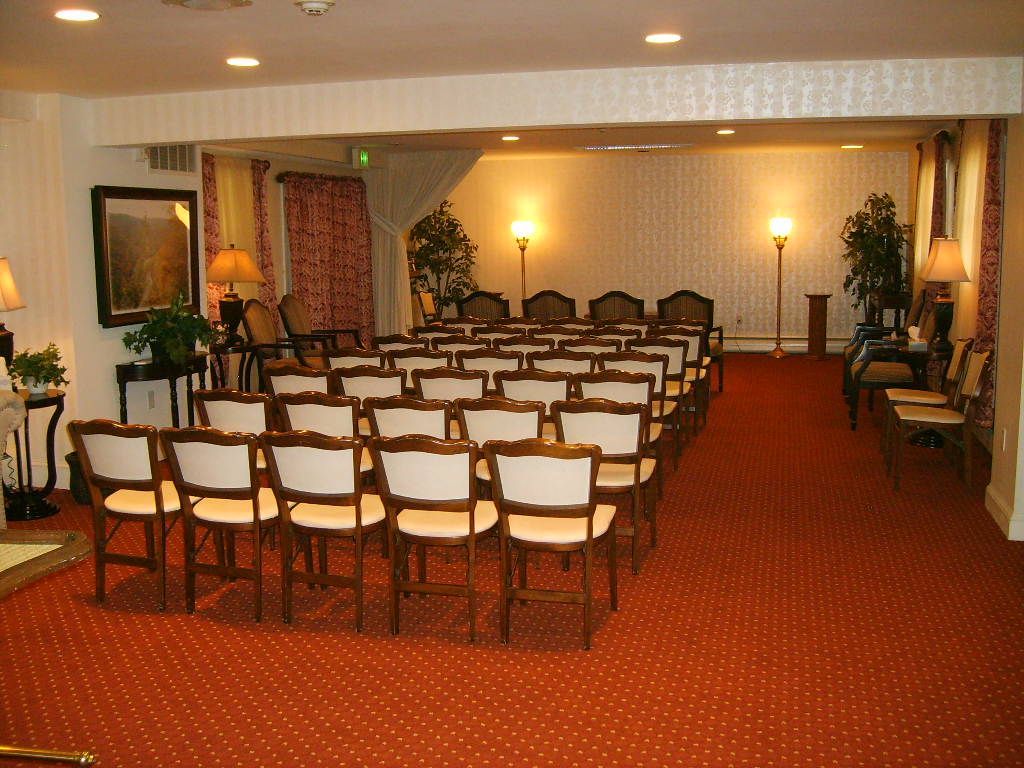 Rows of chairs set up in a room with a red patterned carpet, likely for a ceremony or service.