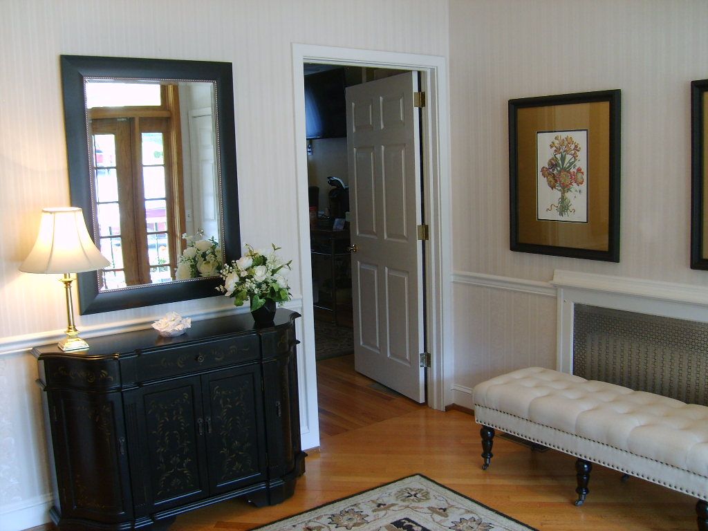 Entryway with black furniture, mirror, and art; a bench and a door leading to another room.