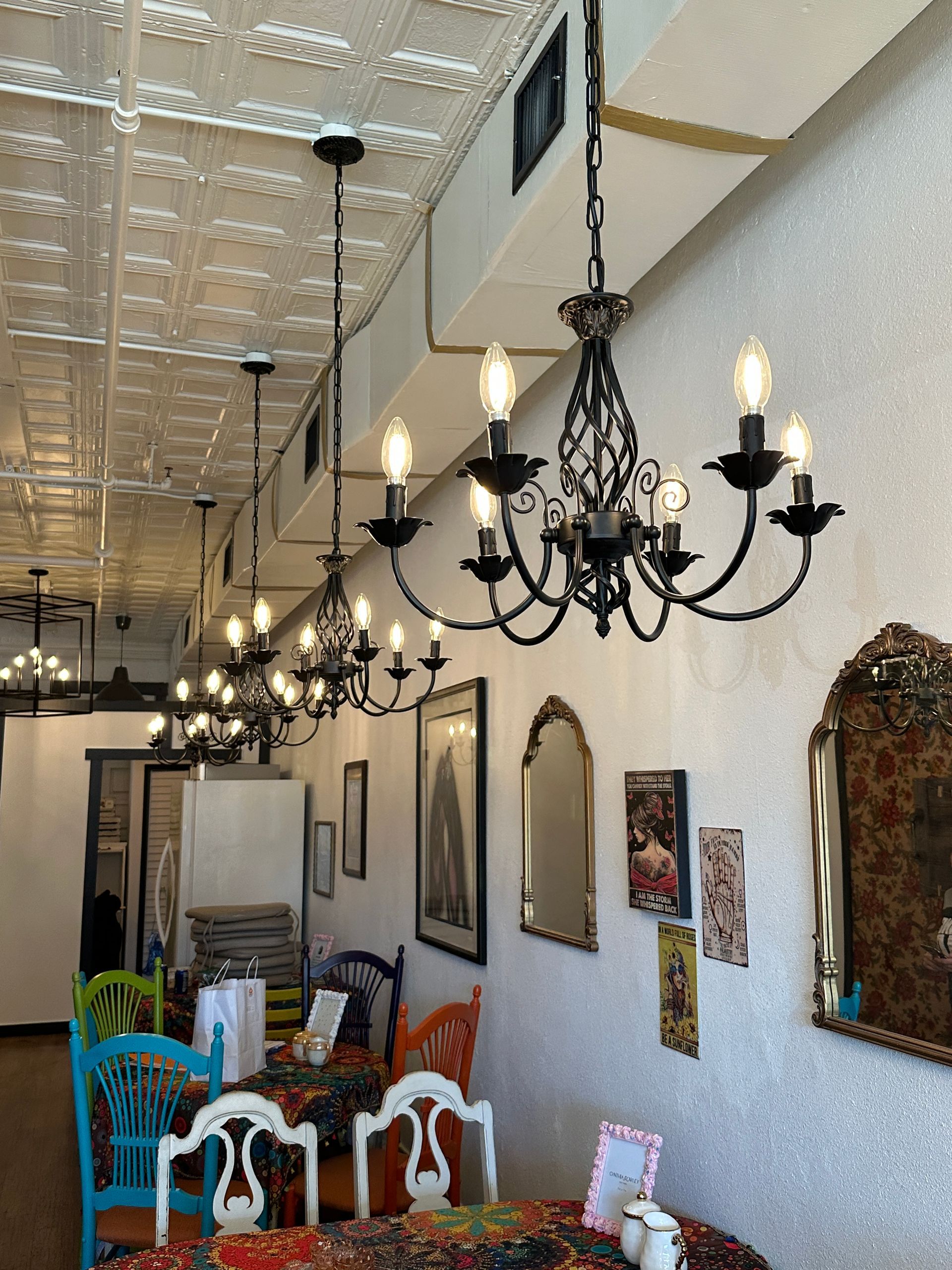 A restaurant with tables and chairs and chandeliers hanging from the ceiling
