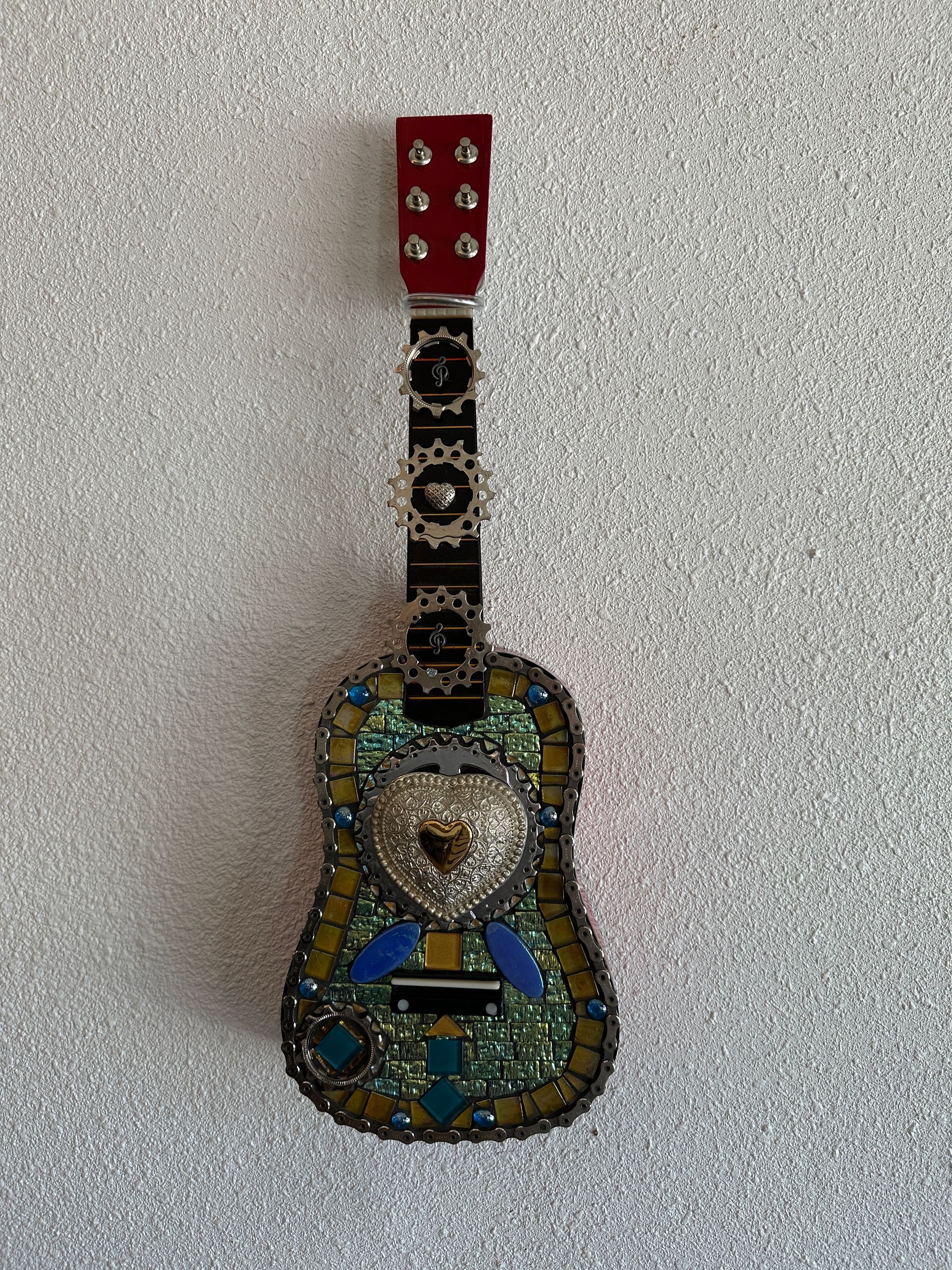 A guitar with a heart on it is hanging on a wall.