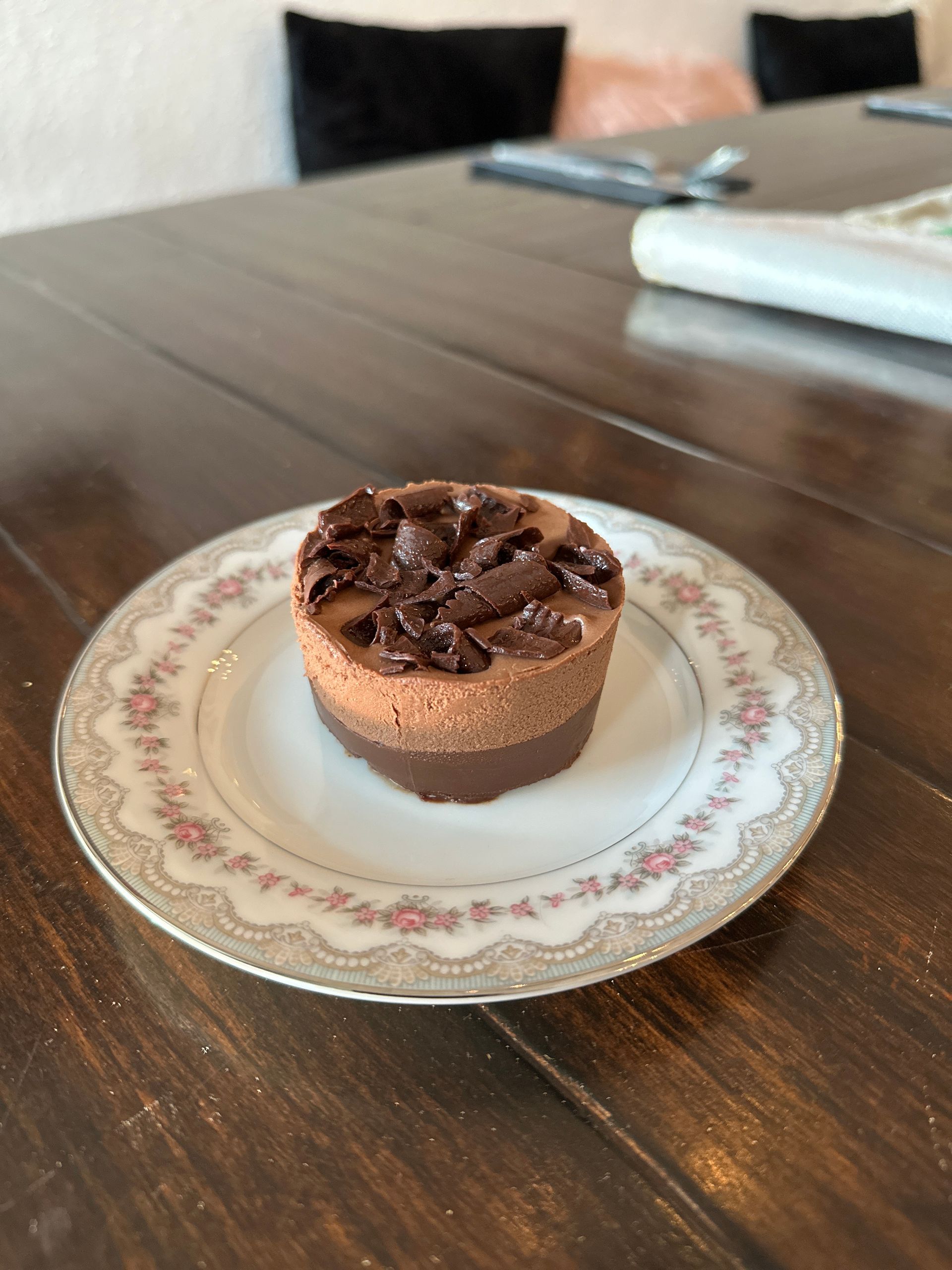 A small chocolate dessert is on a plate on a wooden table.