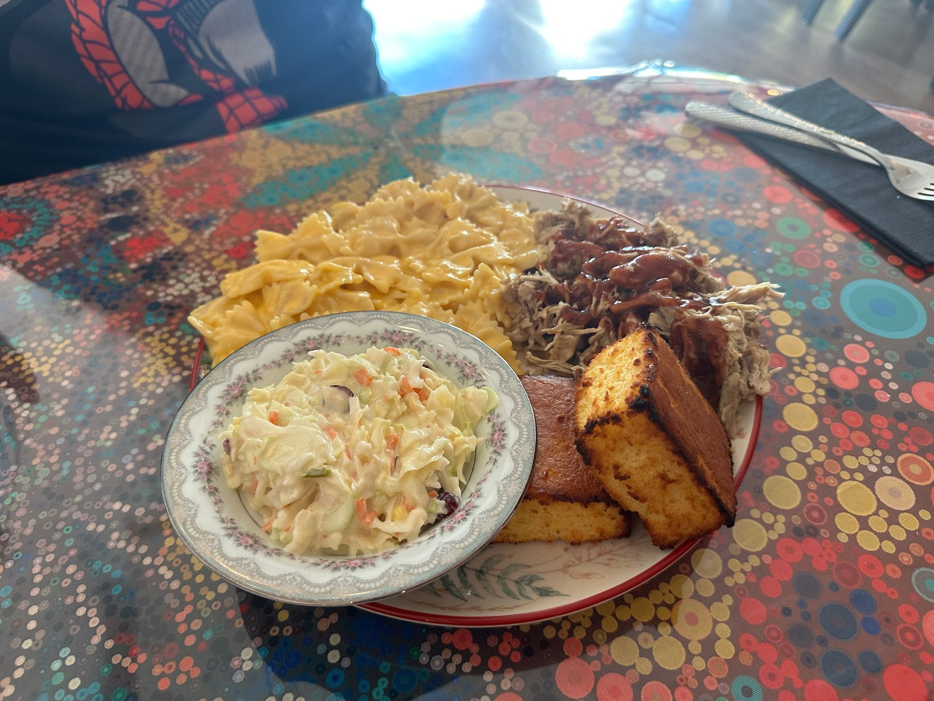 A plate of food with coleslaw and cornbread on a table.