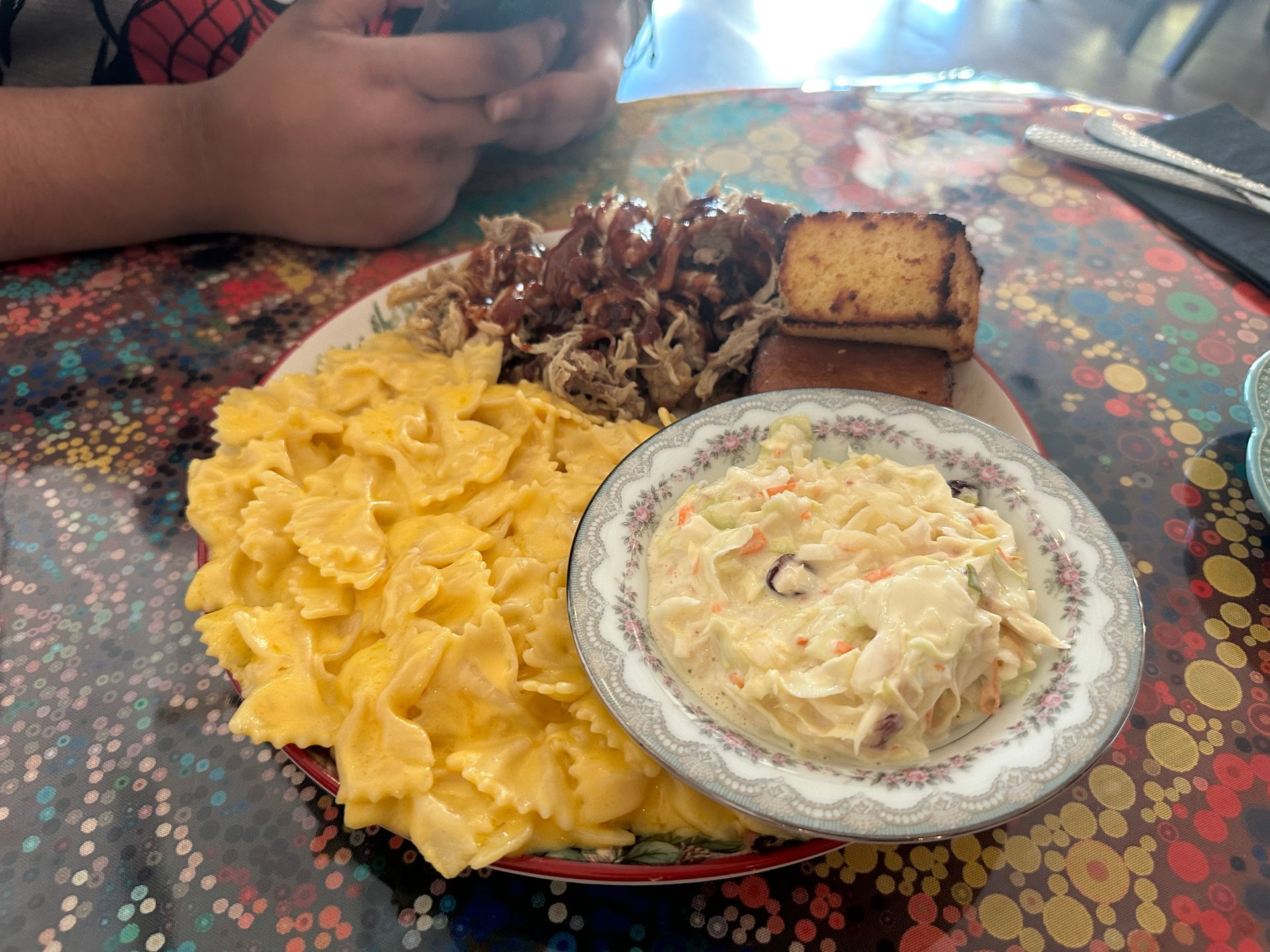 A plate of food on a table with a child looking at his phone.