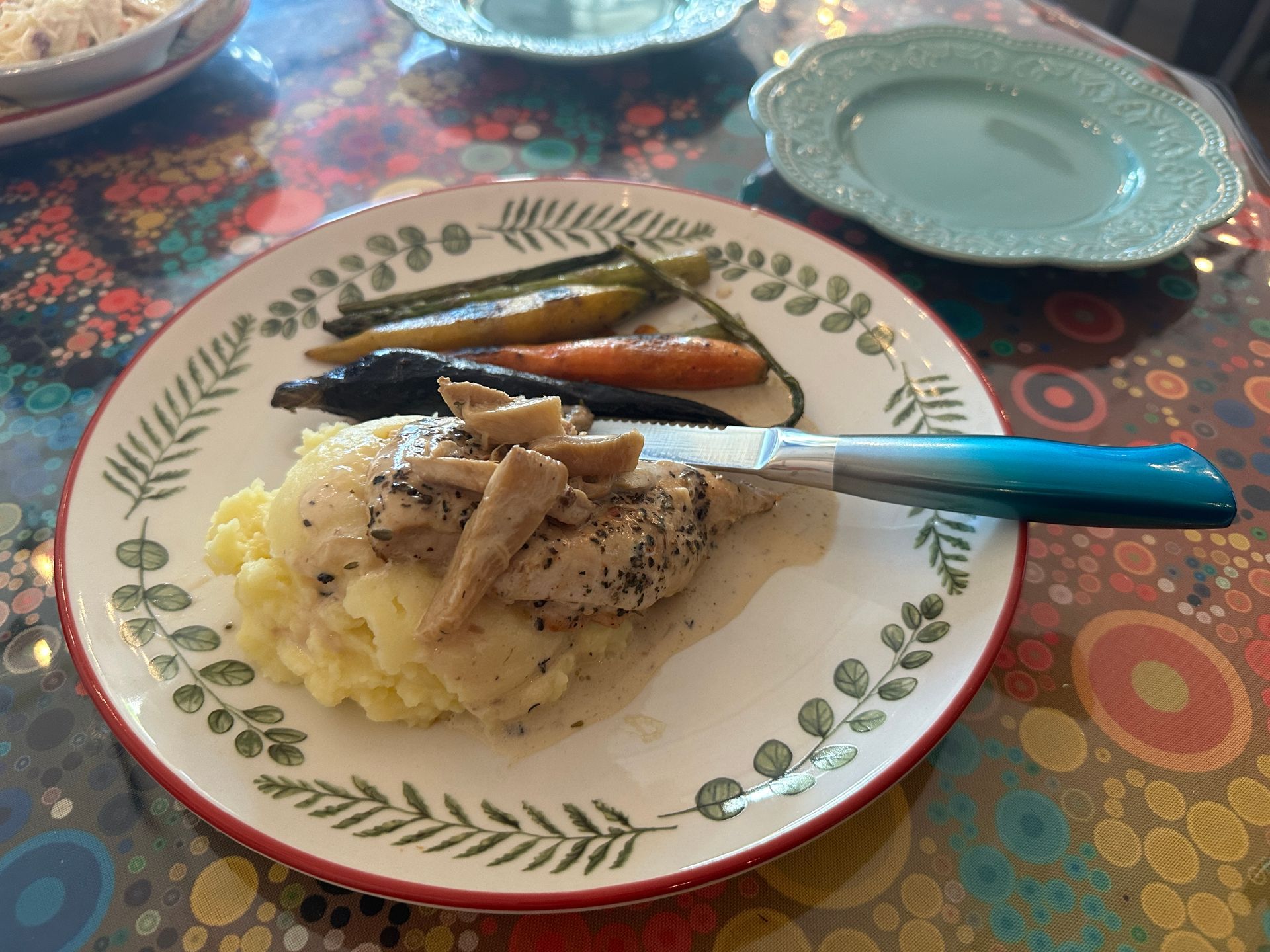 A plate of food with mashed potatoes chicken and carrots on a table.