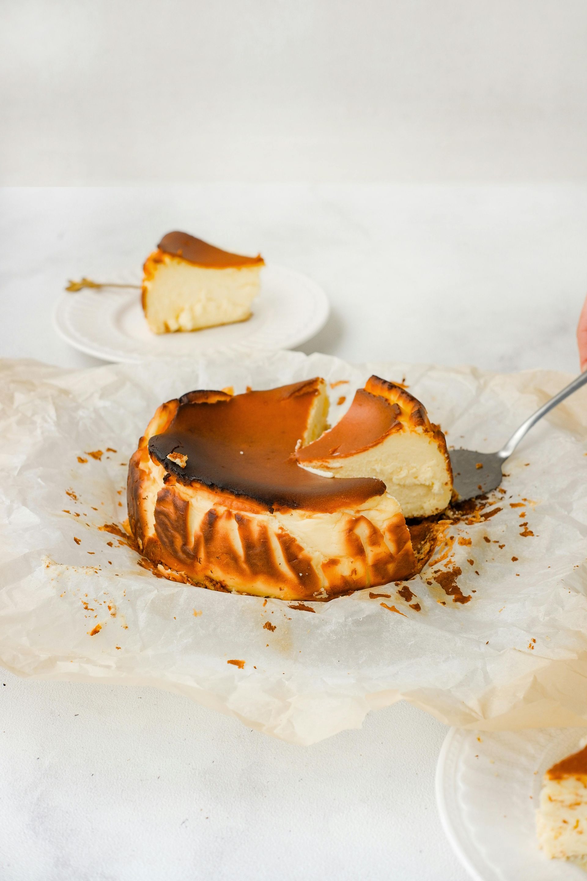 A person is cutting a piece of cheesecake with a spatula.