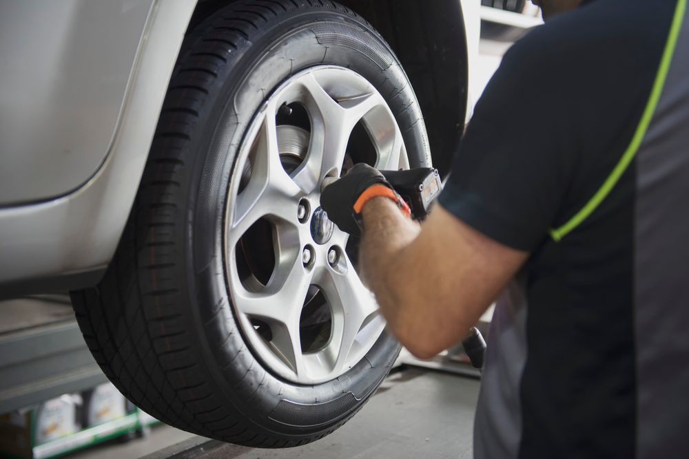 Meccanico che utilizza uno strumento per allentare i dadi delle ruote di un'auto, in un'officina.