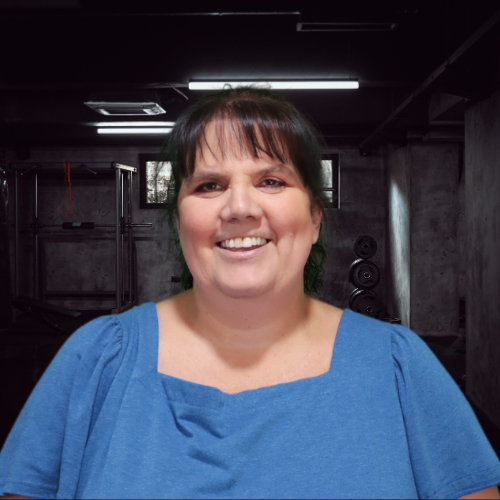 Woman in blue shirt smiles in a dimly lit basement.