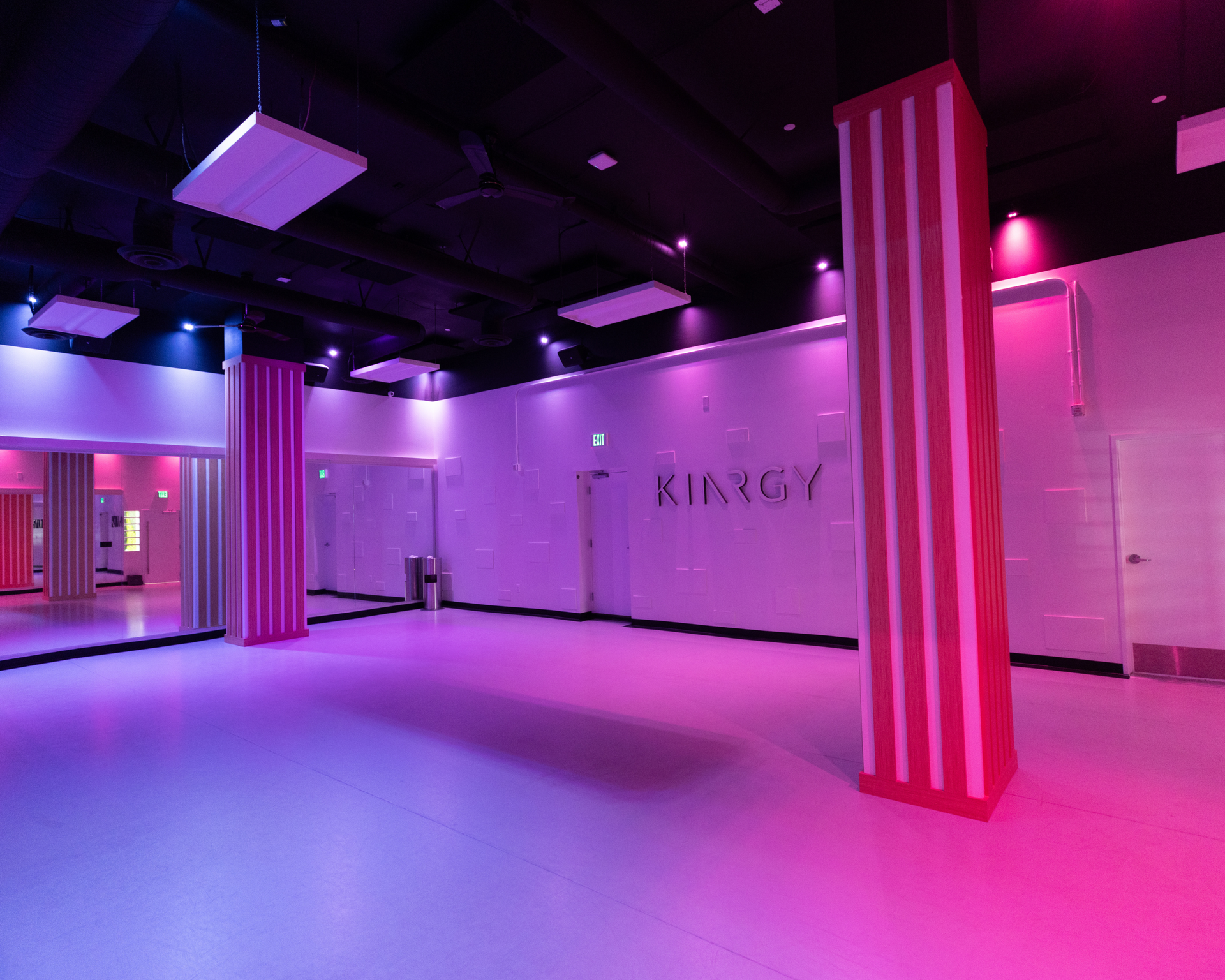 A large empty studio with pink and purple lights and columns.