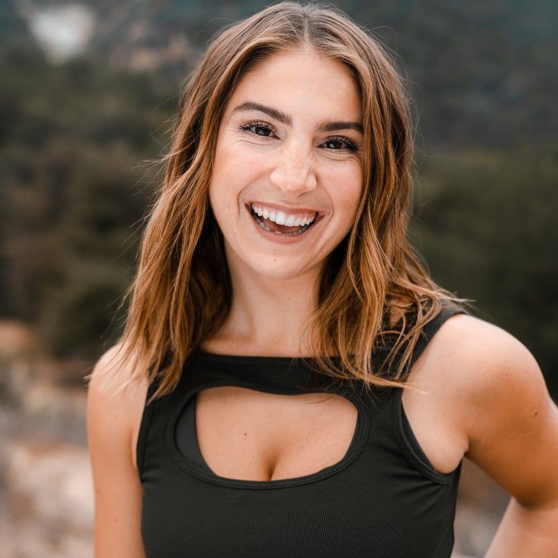 A woman in a black tank top is smiling for the camera.