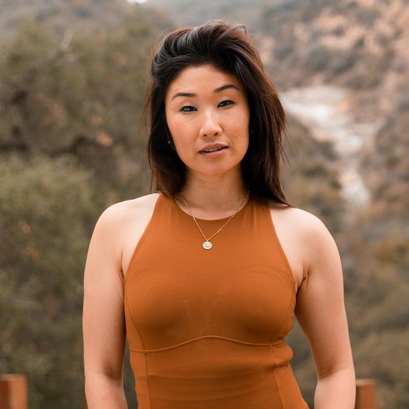 A woman in a brown top and necklace is posing for the camera.