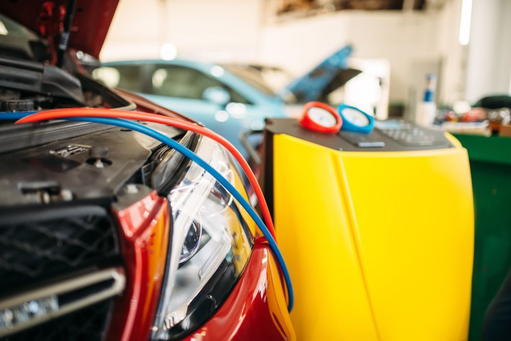 A red car is being serviced by a mechanic in a garage.  — Maroochy Automotive in Kunda Park, QLD