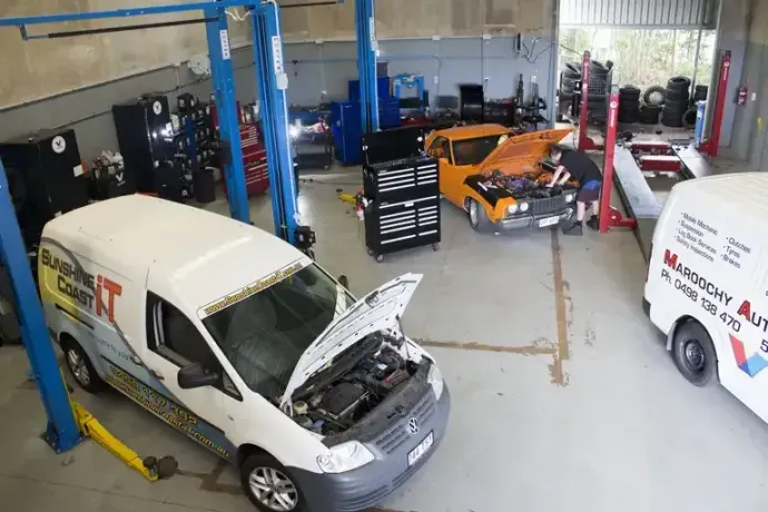 A White Van with The Hood Open Is Sitting on A Lift in A Garage — Maroochy Automotive in Kunda Park, QLD