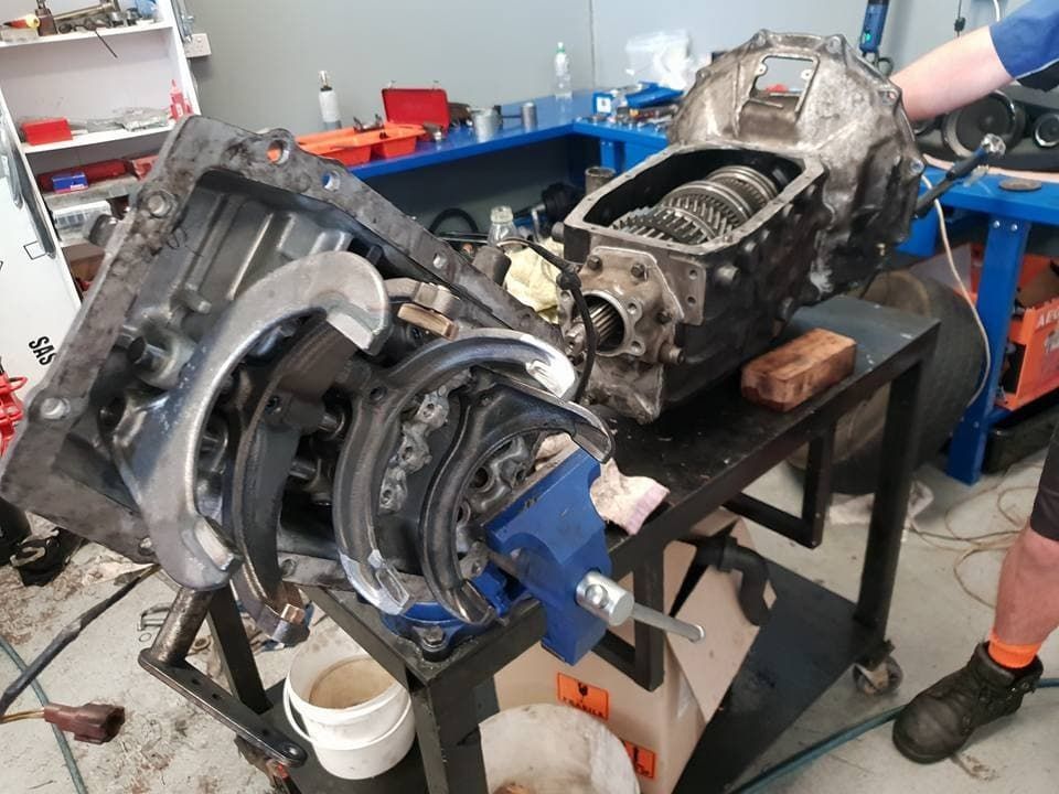 A Man Repairs a Car Engine in a Well-equipped Workshop