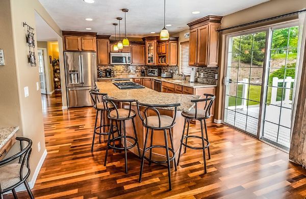 a kitchen with hardwood floors , stainless steel appliances , a large island and stools .