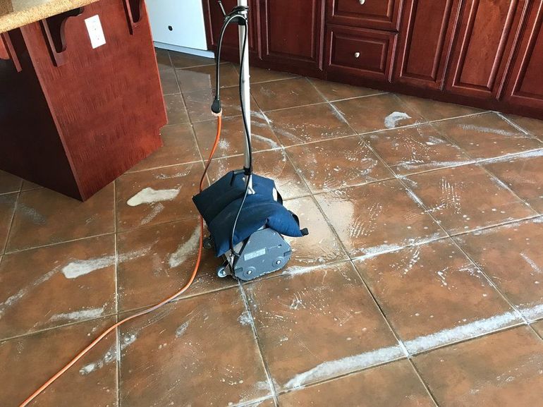 a vacuum cleaner is sitting on a tiled floor in a kitchen
